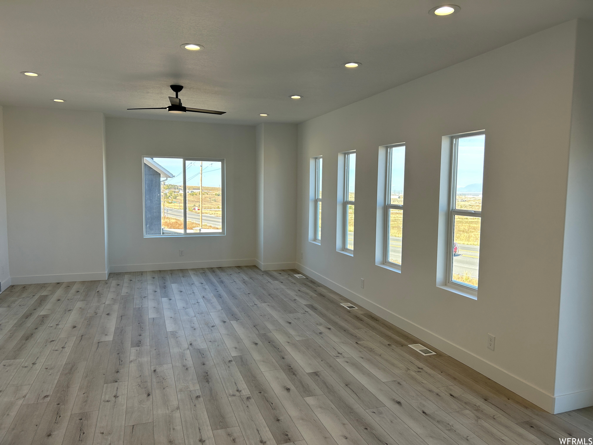 Spare room with light hardwood / wood-style floors, plenty of natural light, and ceiling fan