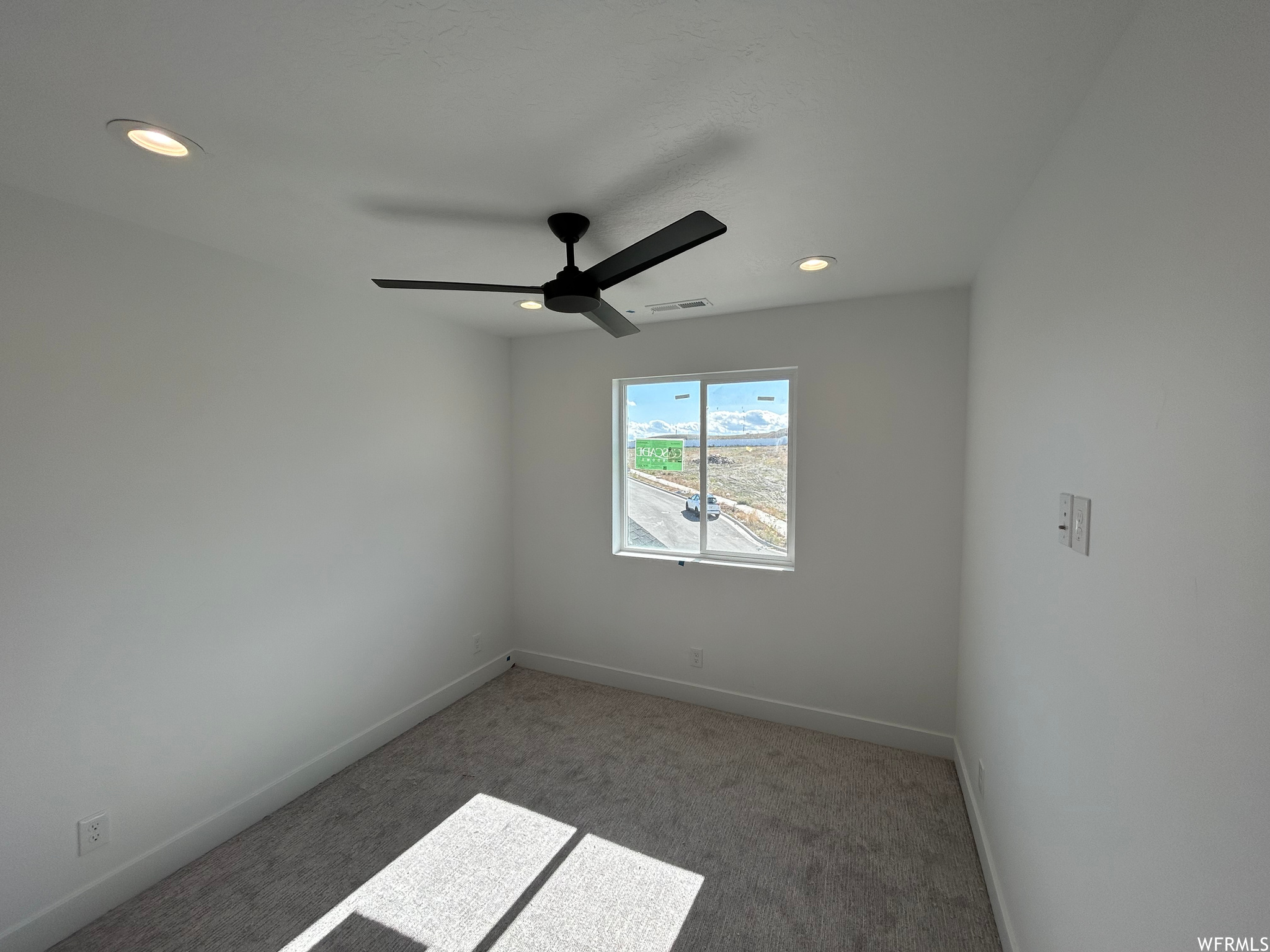 Empty room with ceiling fan and light colored carpet