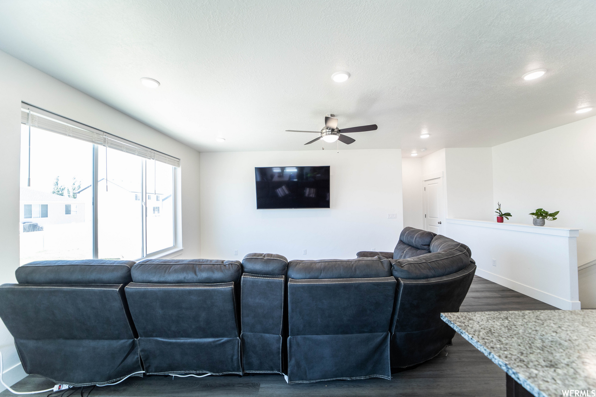 Living room featuring ceiling fan, dark hardwood / wood-style floors, and a textured ceiling