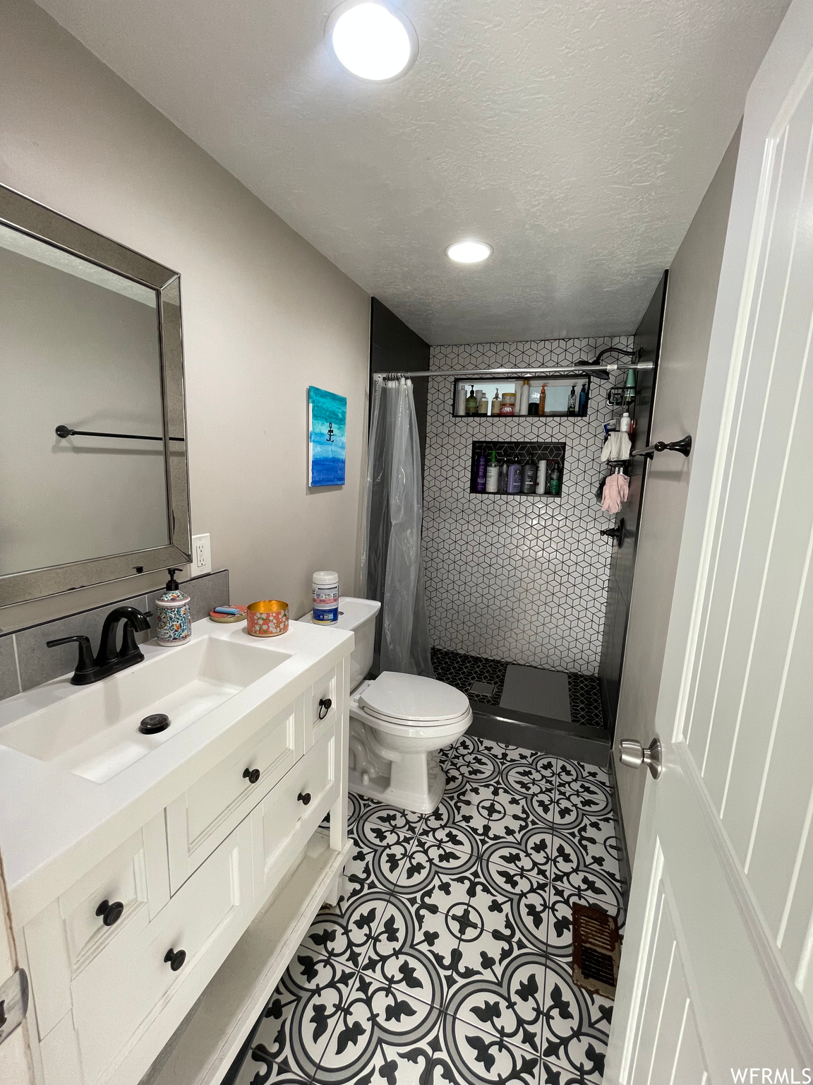 Bathroom featuring oversized vanity, a textured ceiling, toilet, and tile floors