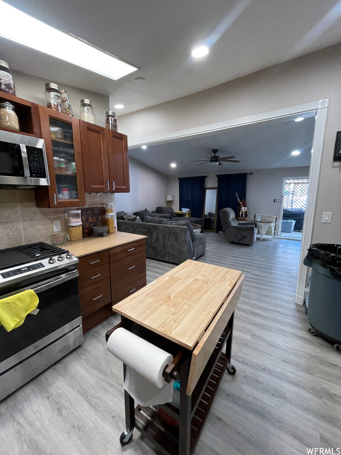 Kitchen featuring stainless steel appliances, ceiling fan, tasteful backsplash, and light hardwood / wood-style flooring