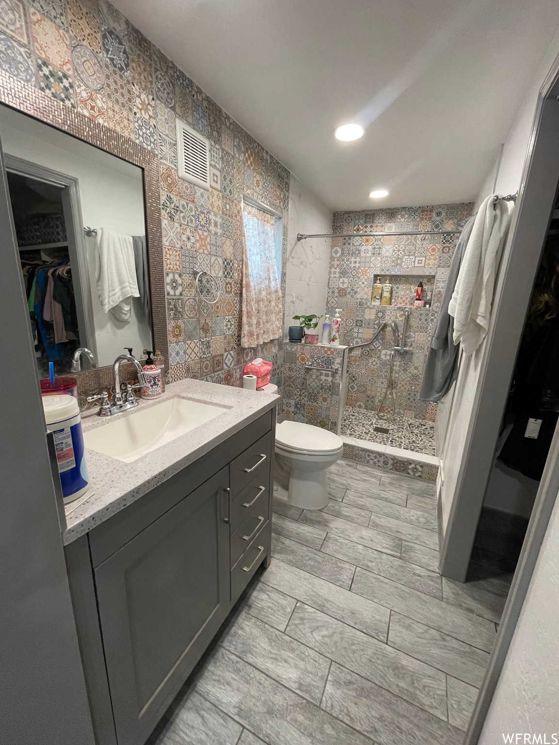 Bathroom with a shower, vanity with extensive cabinet space, and toilet