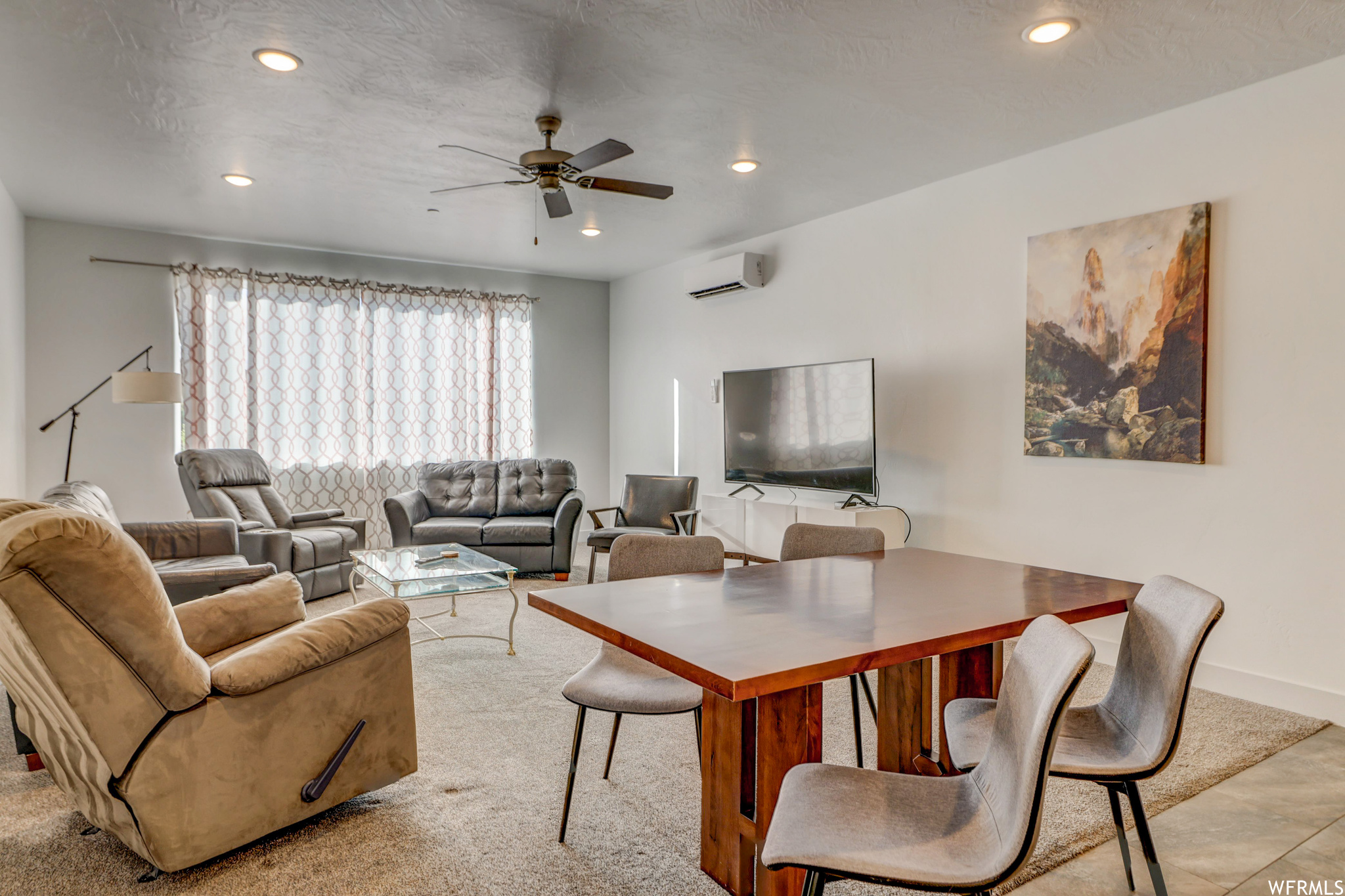 Living room with ceiling fan and a wall mounted air conditioner