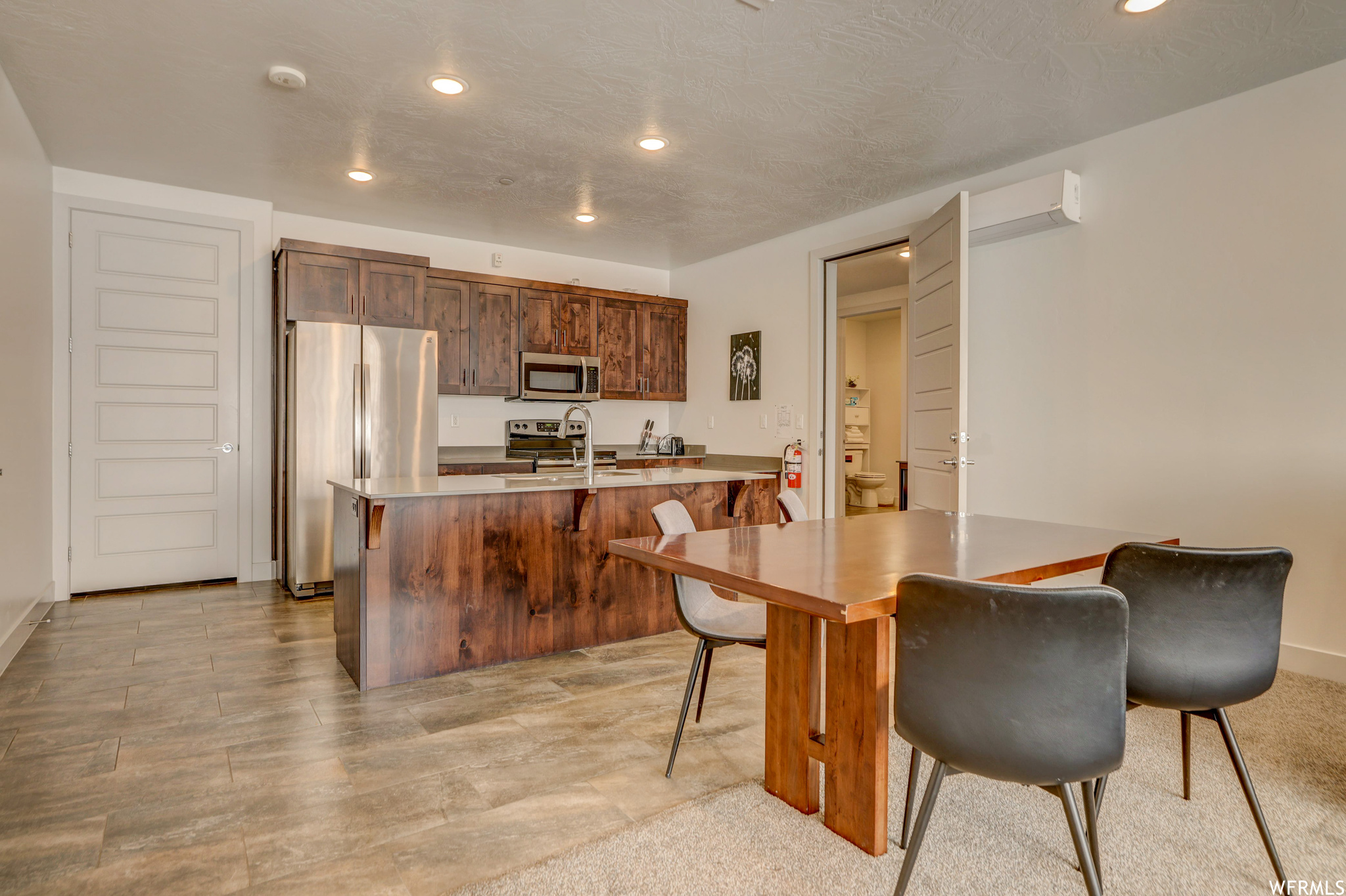 Kitchen featuring sink, a breakfast bar area, light tile floors, a kitchen island with sink, and appliances with stainless steel finishes