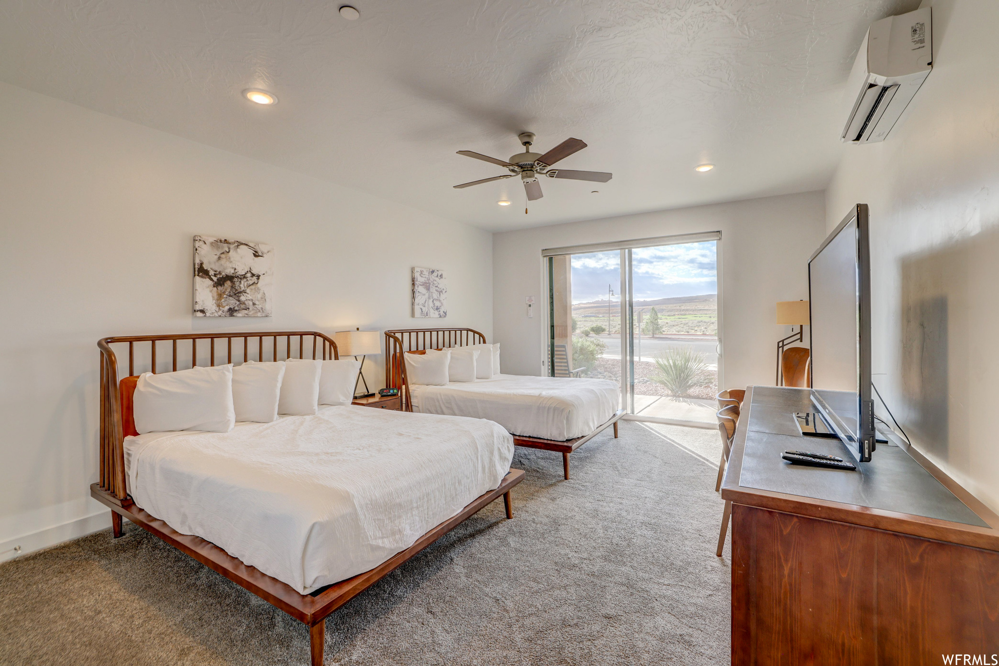 Bedroom featuring a wall mounted AC, ceiling fan, light carpet, and access to exterior