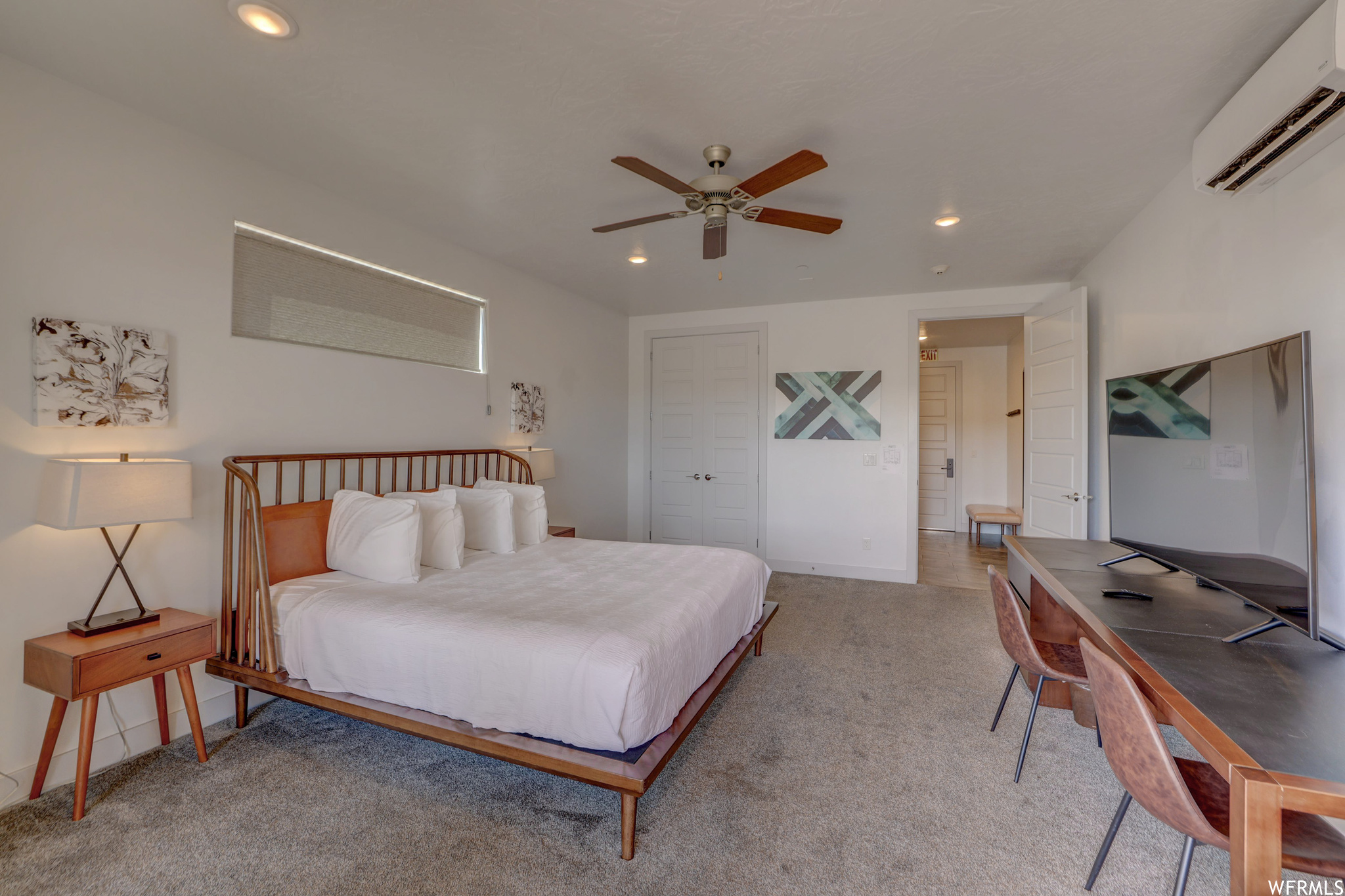 Bedroom with ceiling fan, a wall unit AC, and light colored carpet