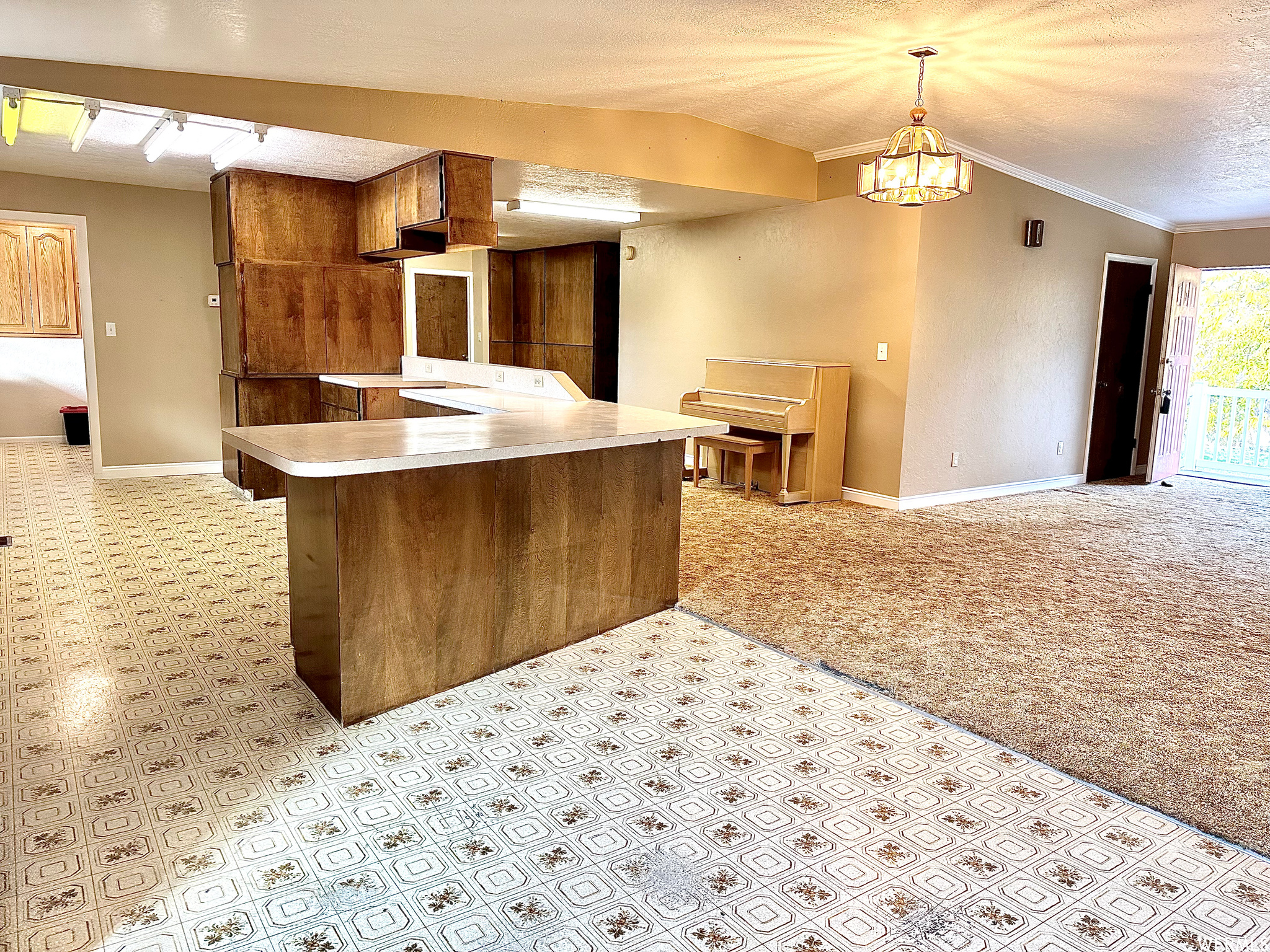 Kitchen featuring decorative light fixtures, light tile floors, a textured ceiling, range, and ornamental molding