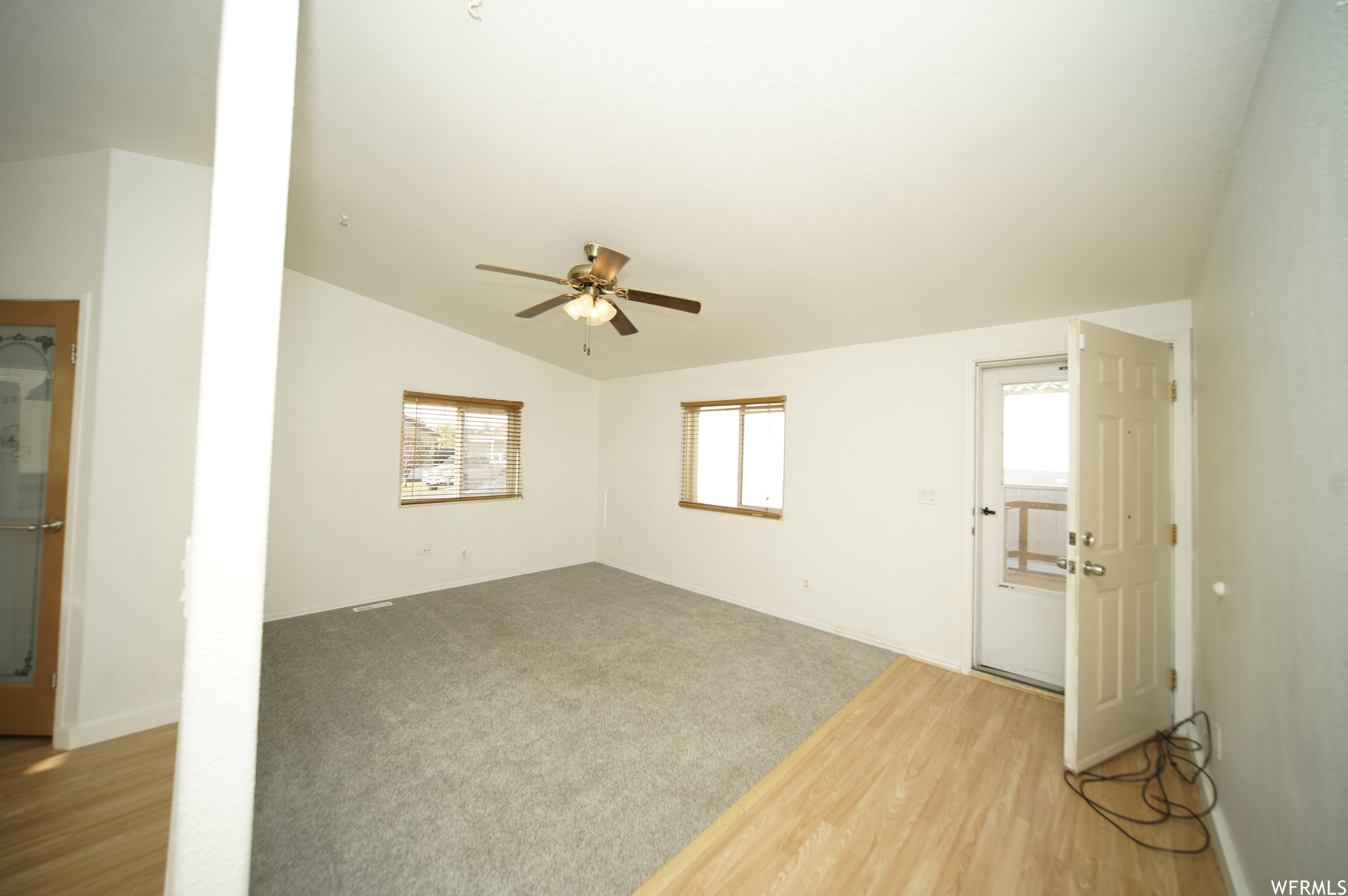 Unfurnished room with vaulted ceiling, ceiling fan, and light colored carpet