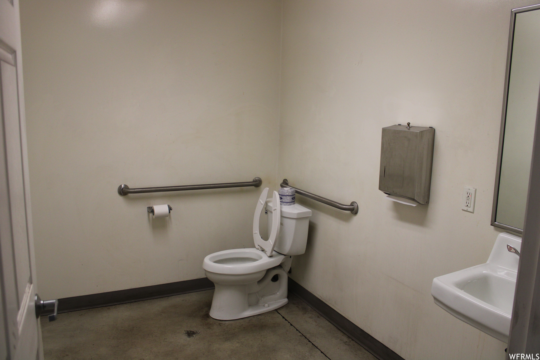 Bathroom featuring sink, toilet, and concrete floors