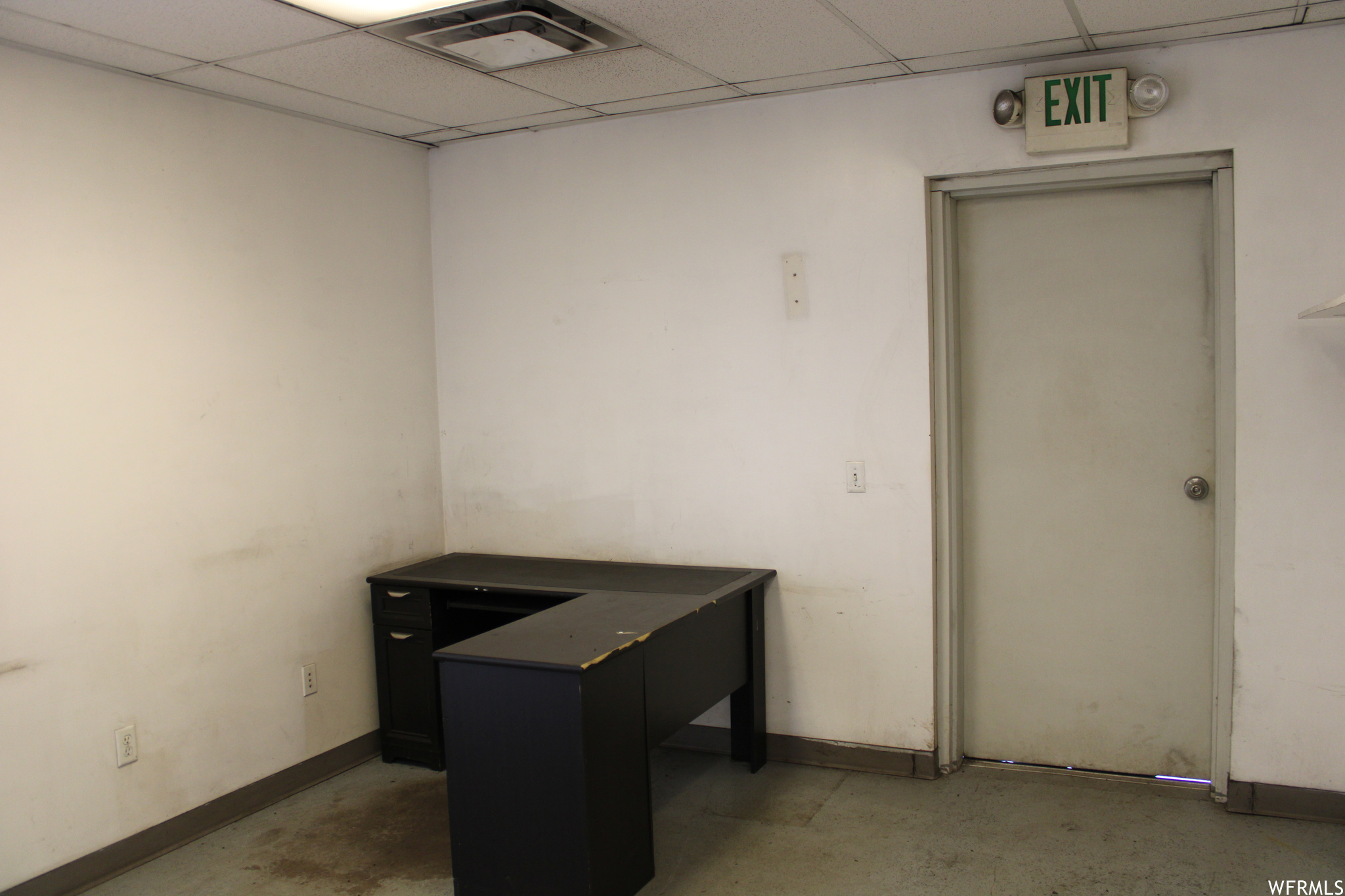 Unfurnished office featuring concrete floors and a drop ceiling