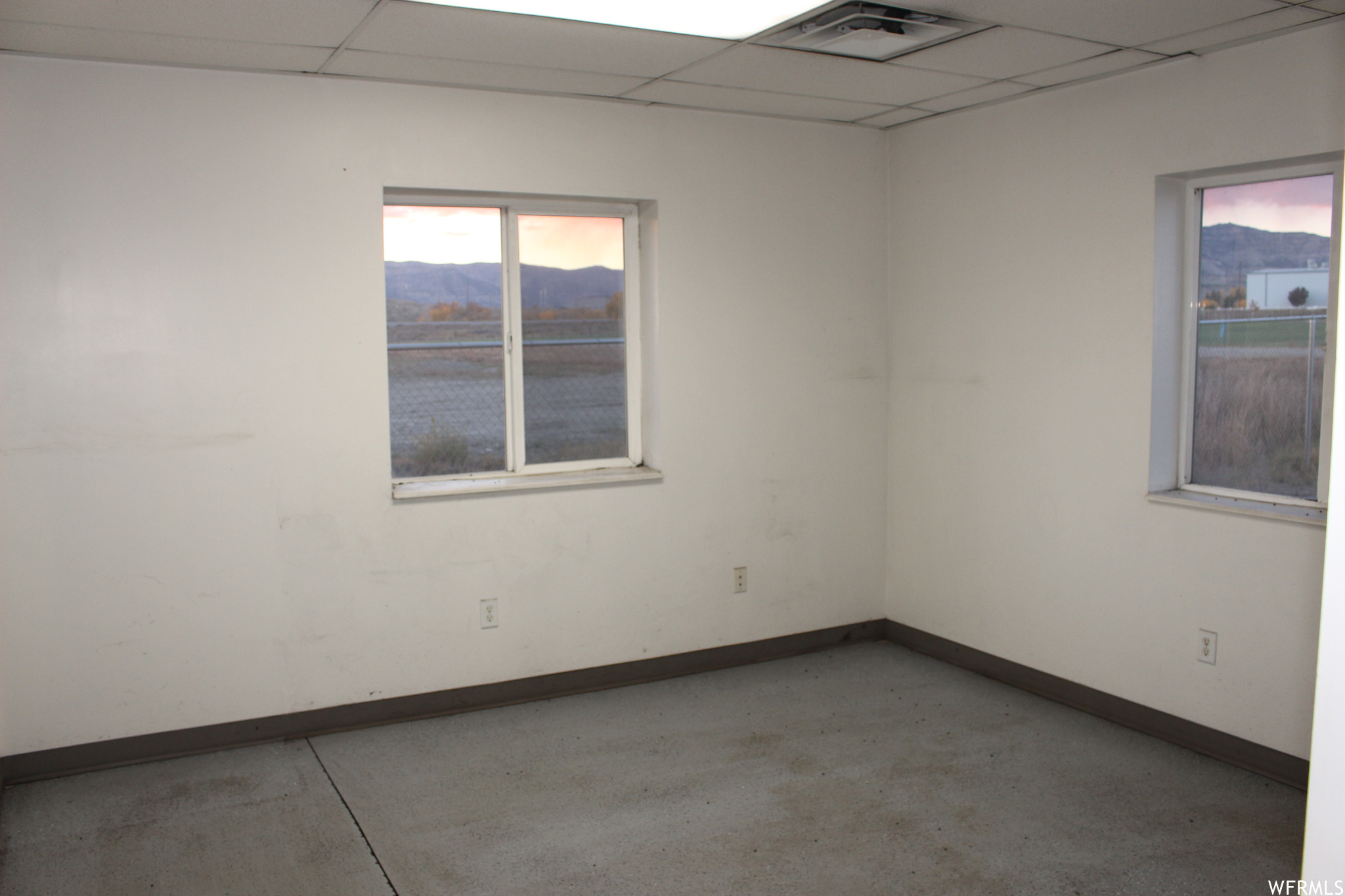 Spare room with concrete floors, a mountain view, and a drop ceiling