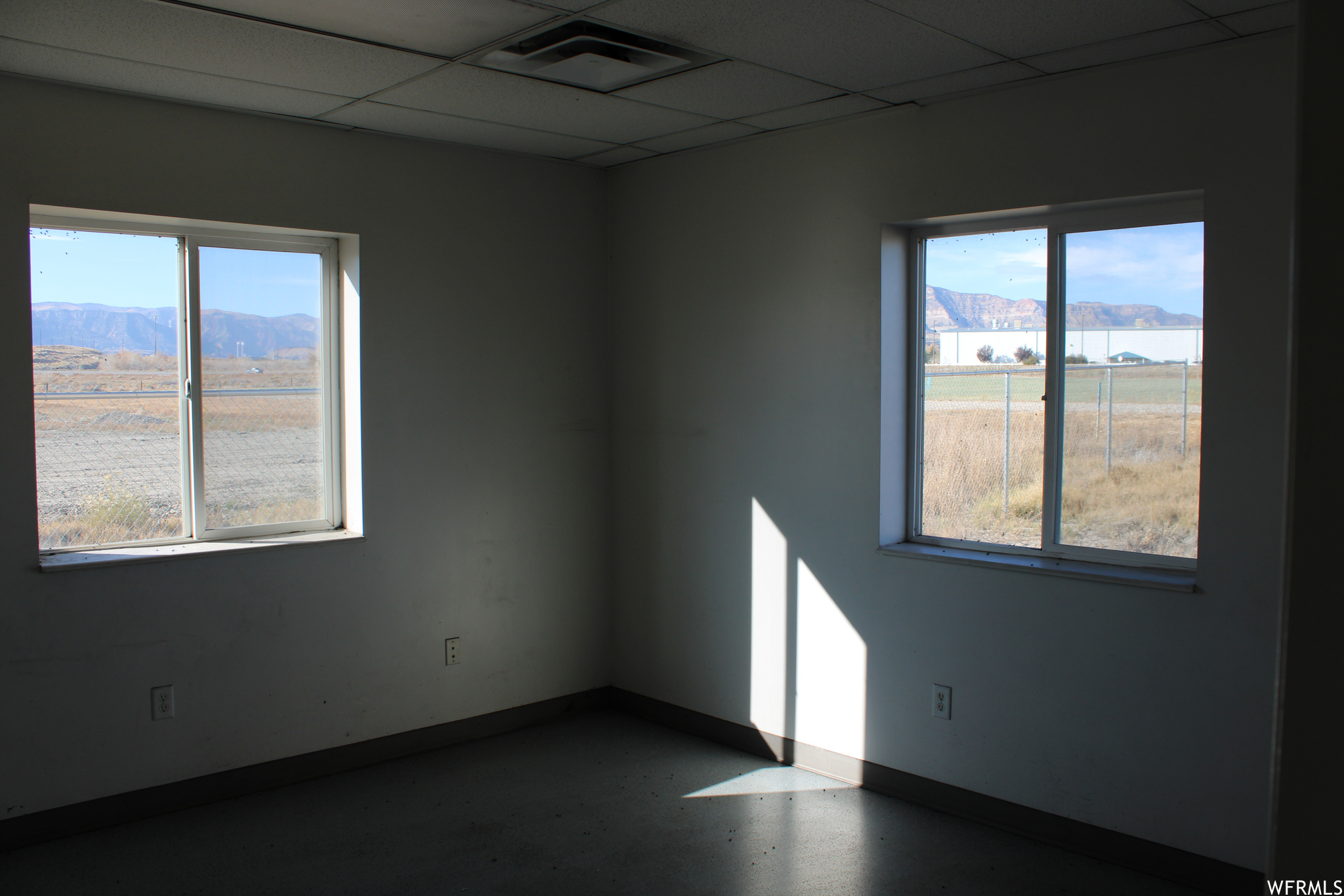 Spare room with a paneled ceiling, concrete flooring, and a mountain view