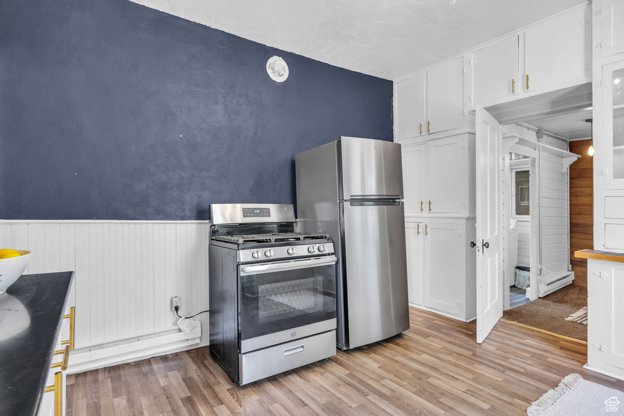 Kitchen featuring white cabinets,  wood-type flooring, and stainless steel appliances