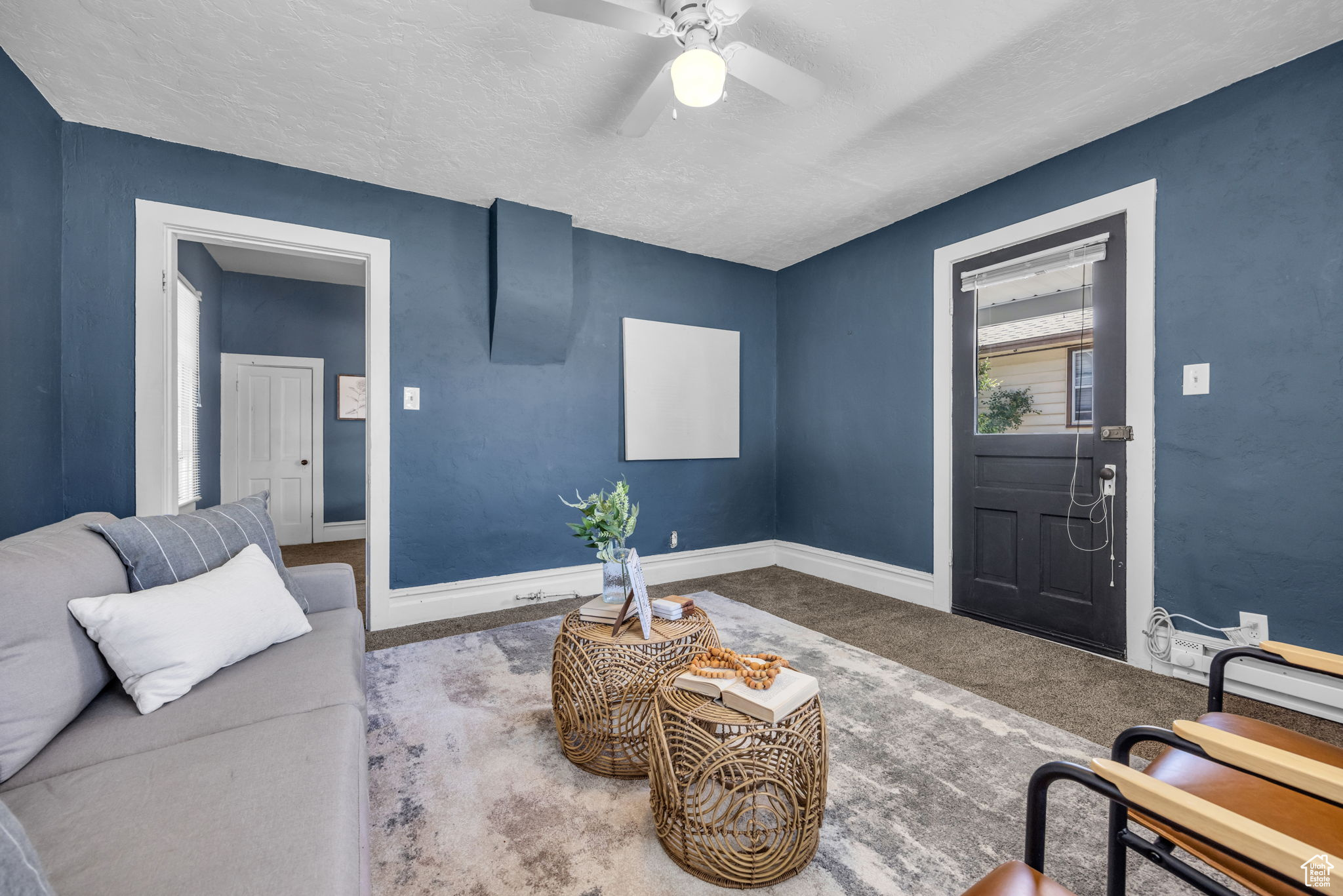 Carpeted living room with ceiling fan and a textured ceiling