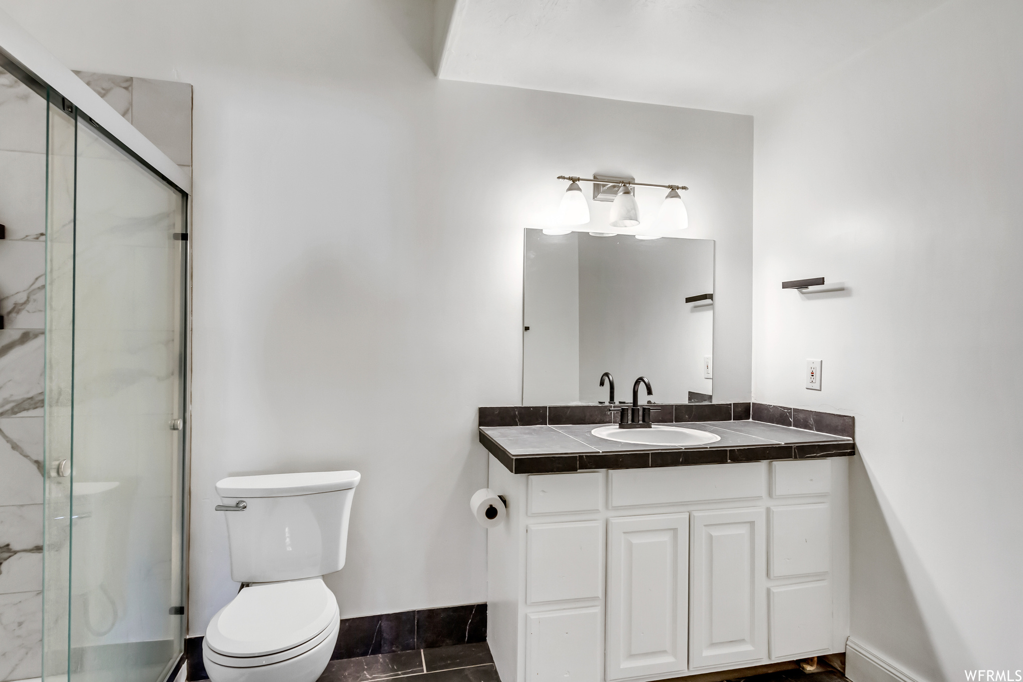 Bathroom featuring vanity, tile flooring, walk in shower, and toilet