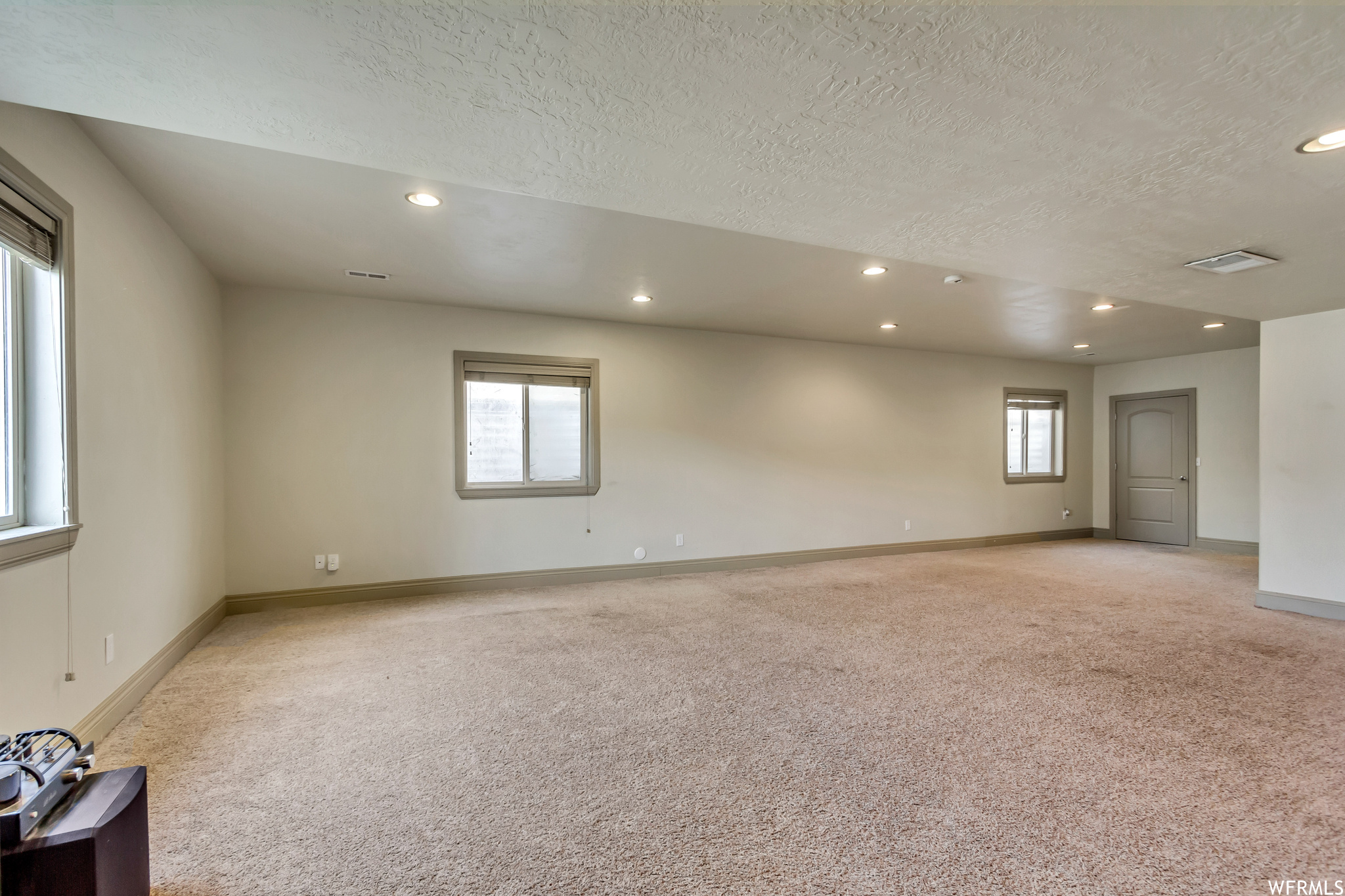 Unfurnished room with plenty of natural light, light colored carpet, and a textured ceiling