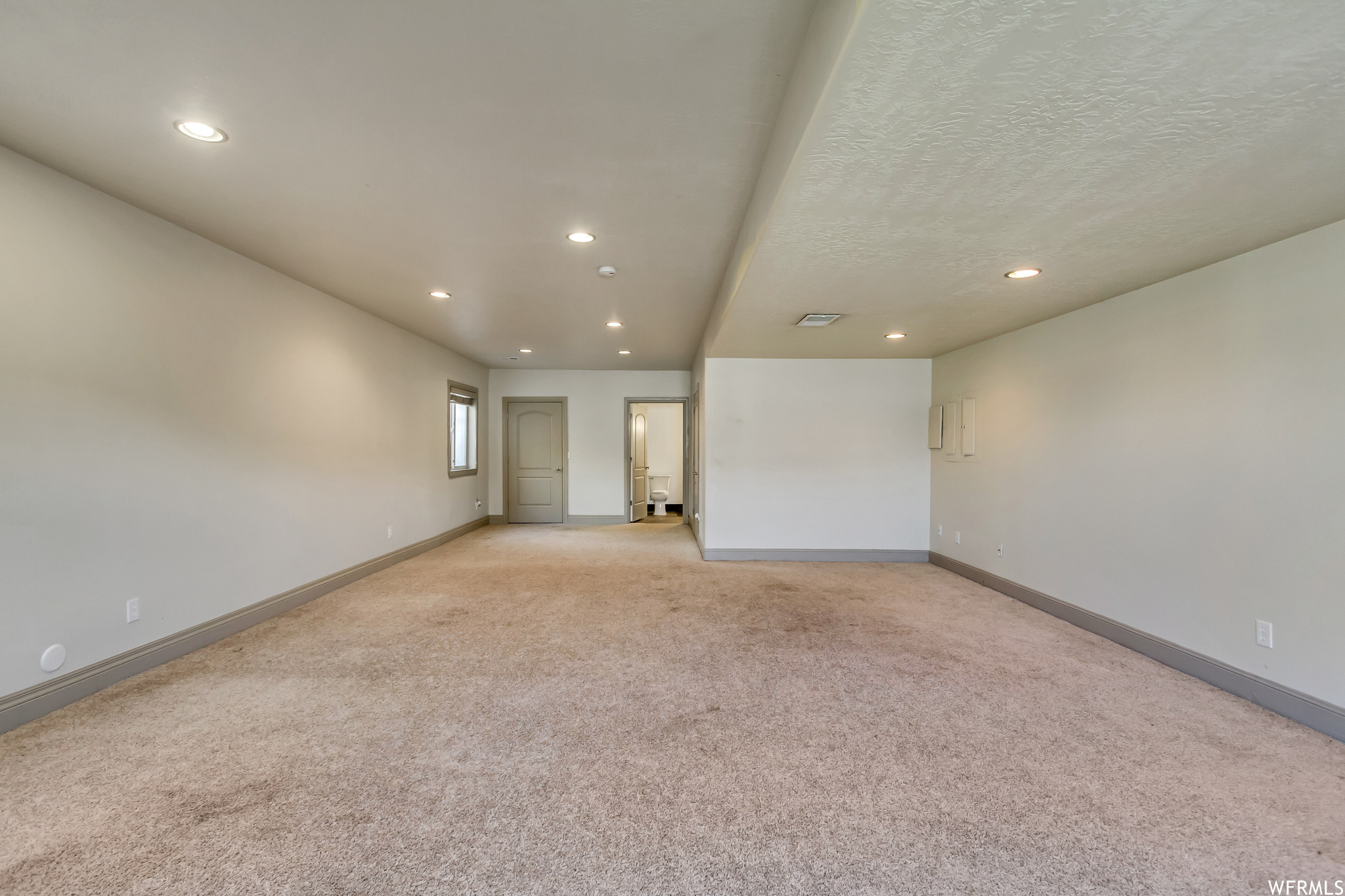 Empty room featuring light carpet and a textured ceiling