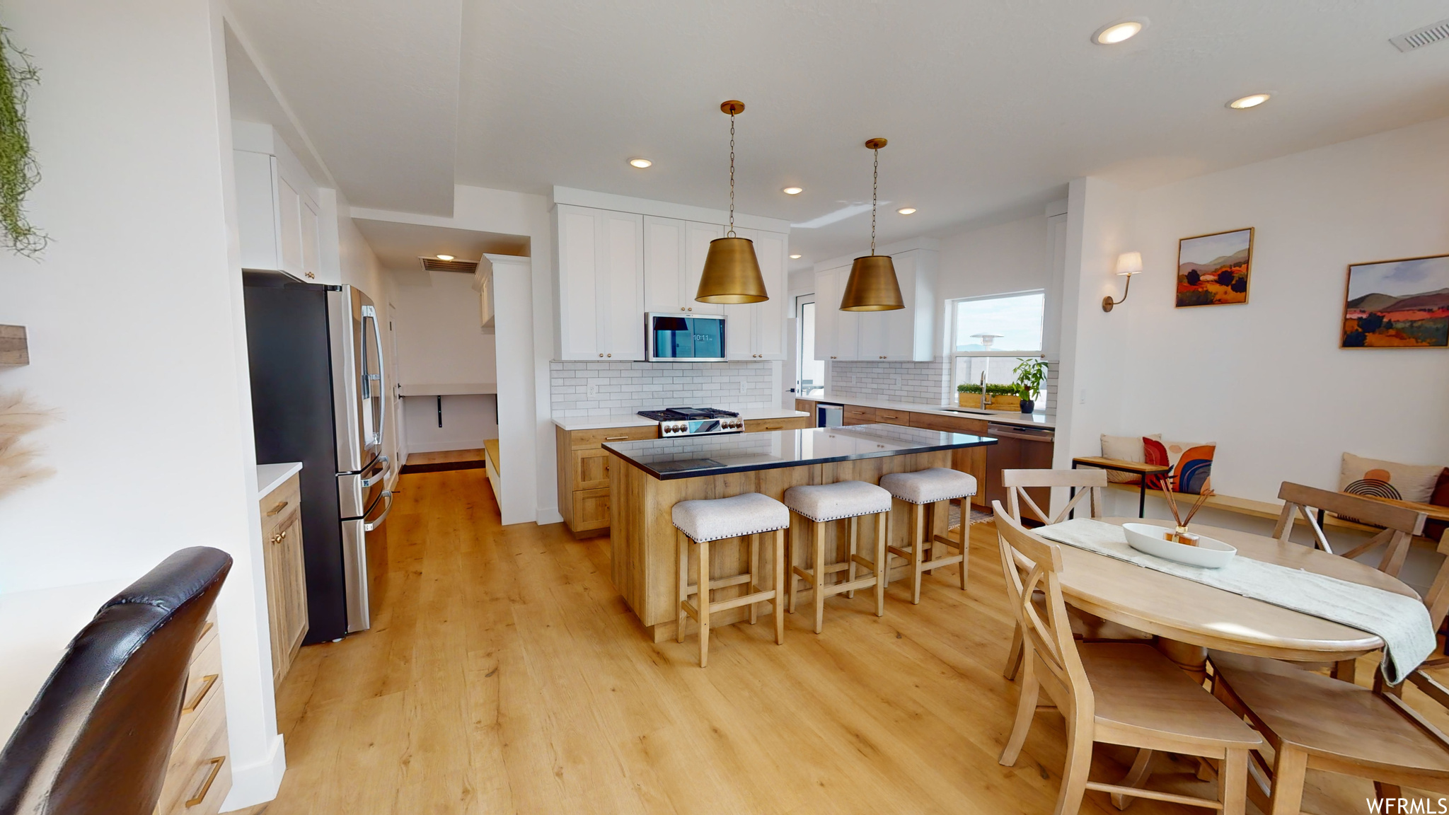 Kitchen featuring hanging light fixtures, light wood-type flooring, a center island, and white cabinets