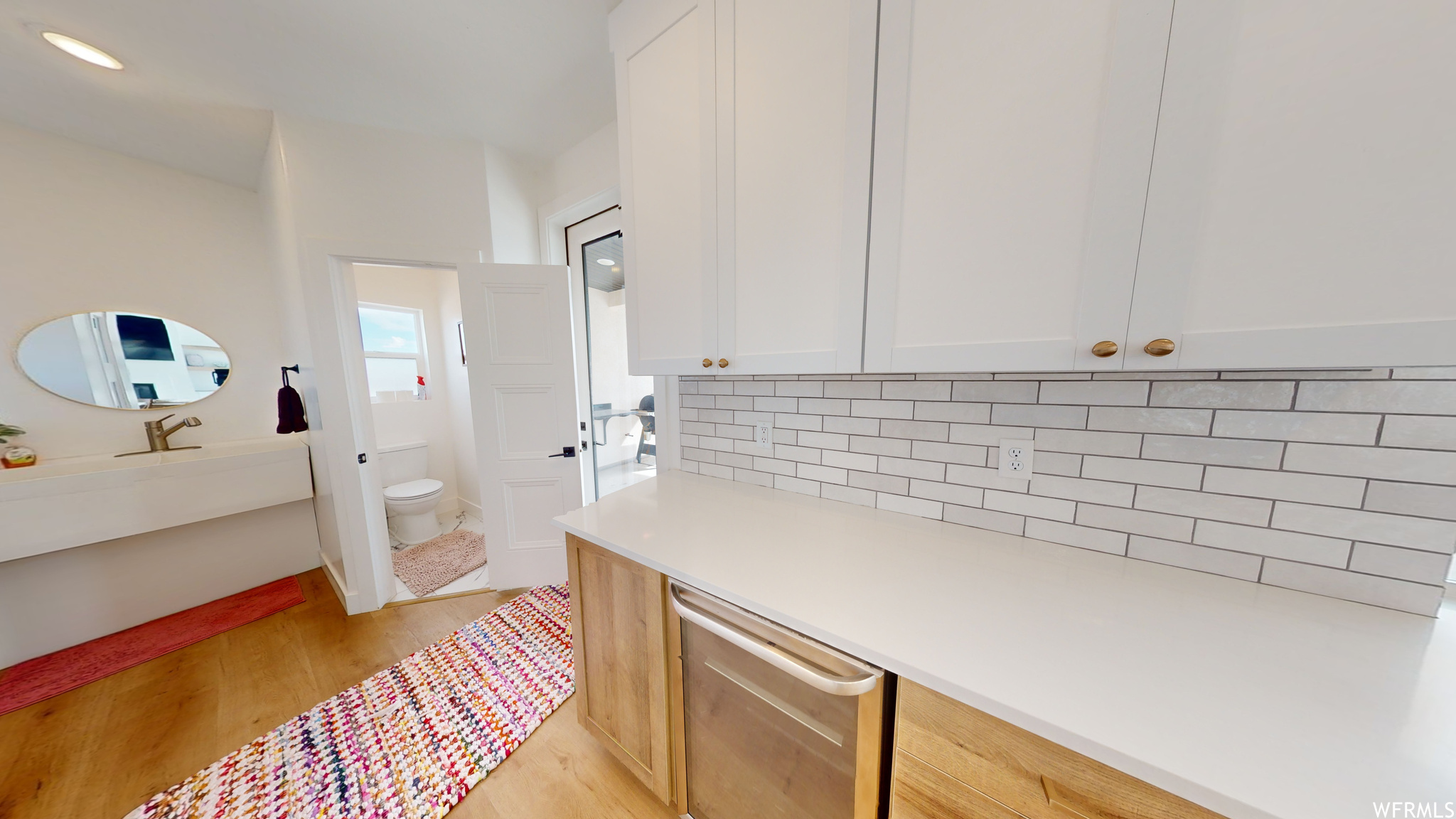 Kitchen with light hardwood / wood-style floors, backsplash, and white cabinets