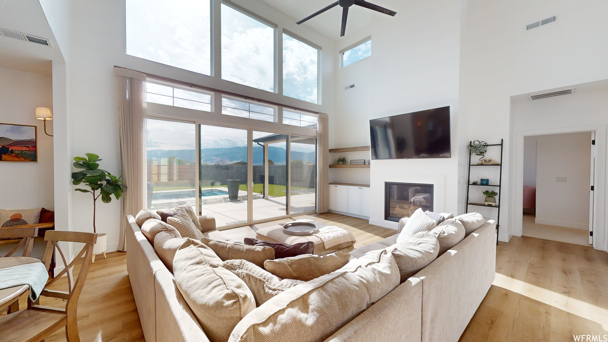 Living room with light hardwood / wood-style floors, a wealth of natural light, a high ceiling, and a mountain view