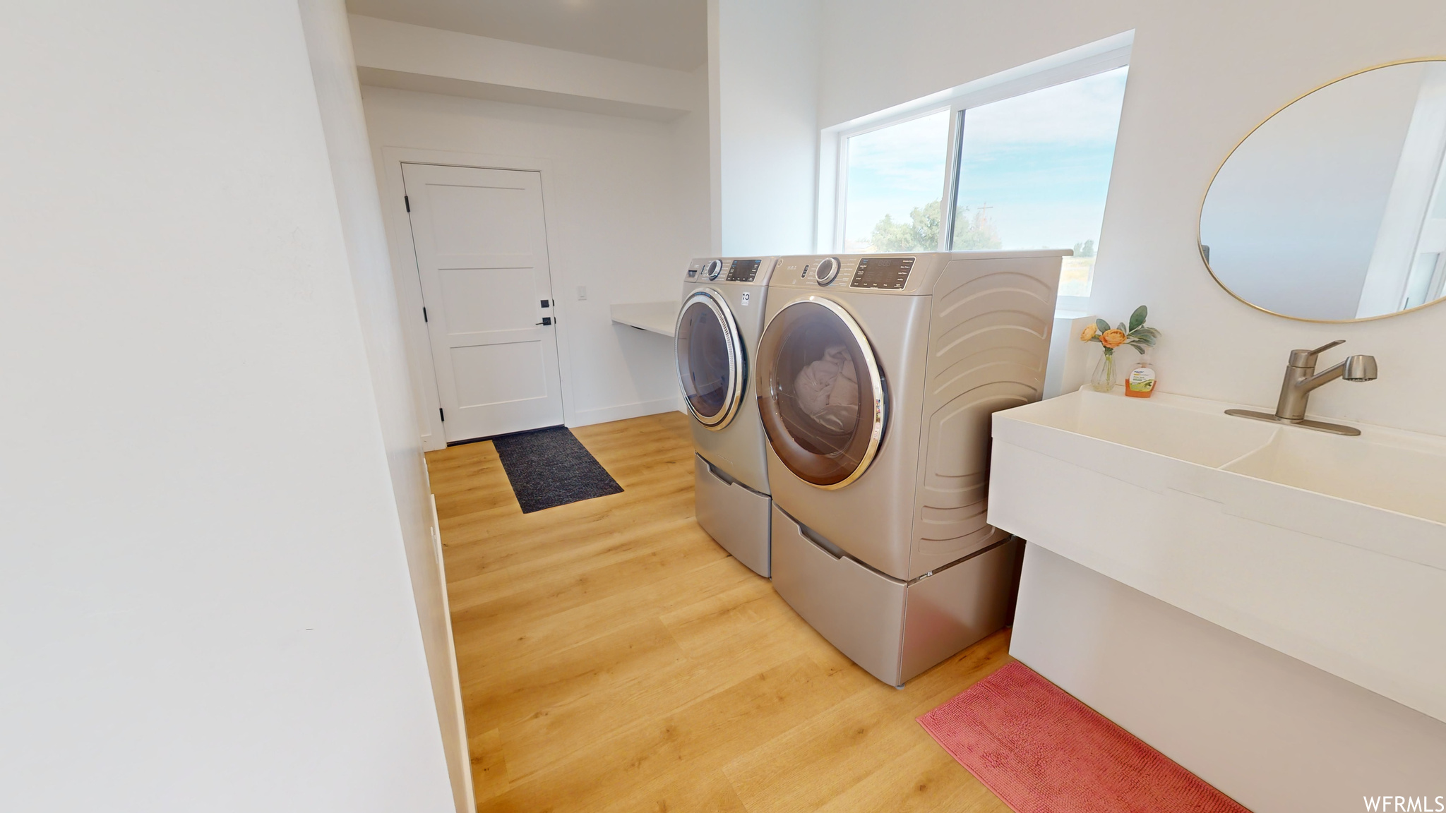 Clothes washing area with washer and dryer and light hardwood / wood-style floors