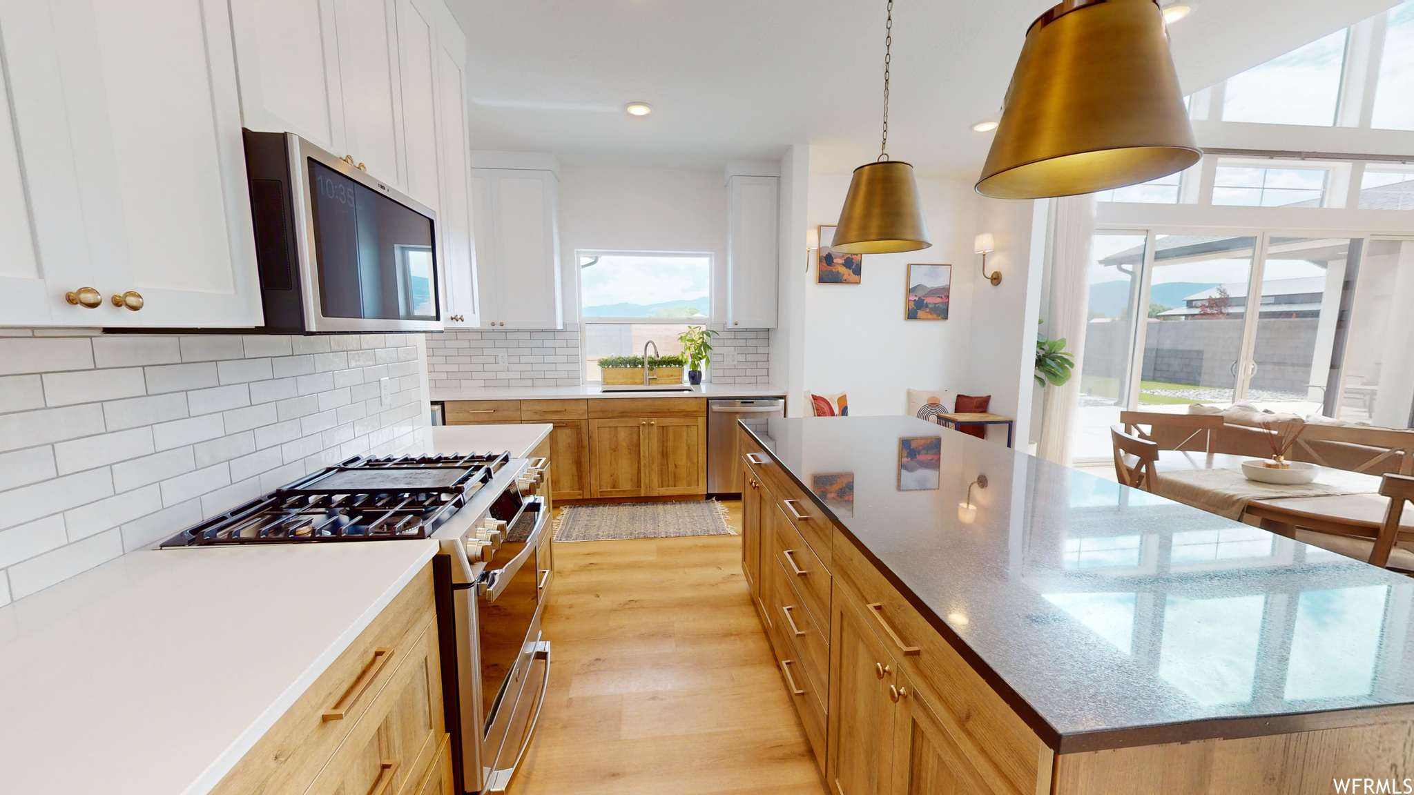 Kitchen featuring sink, tasteful backsplash, white cabinetry, light wood-type flooring, and pendant lighting