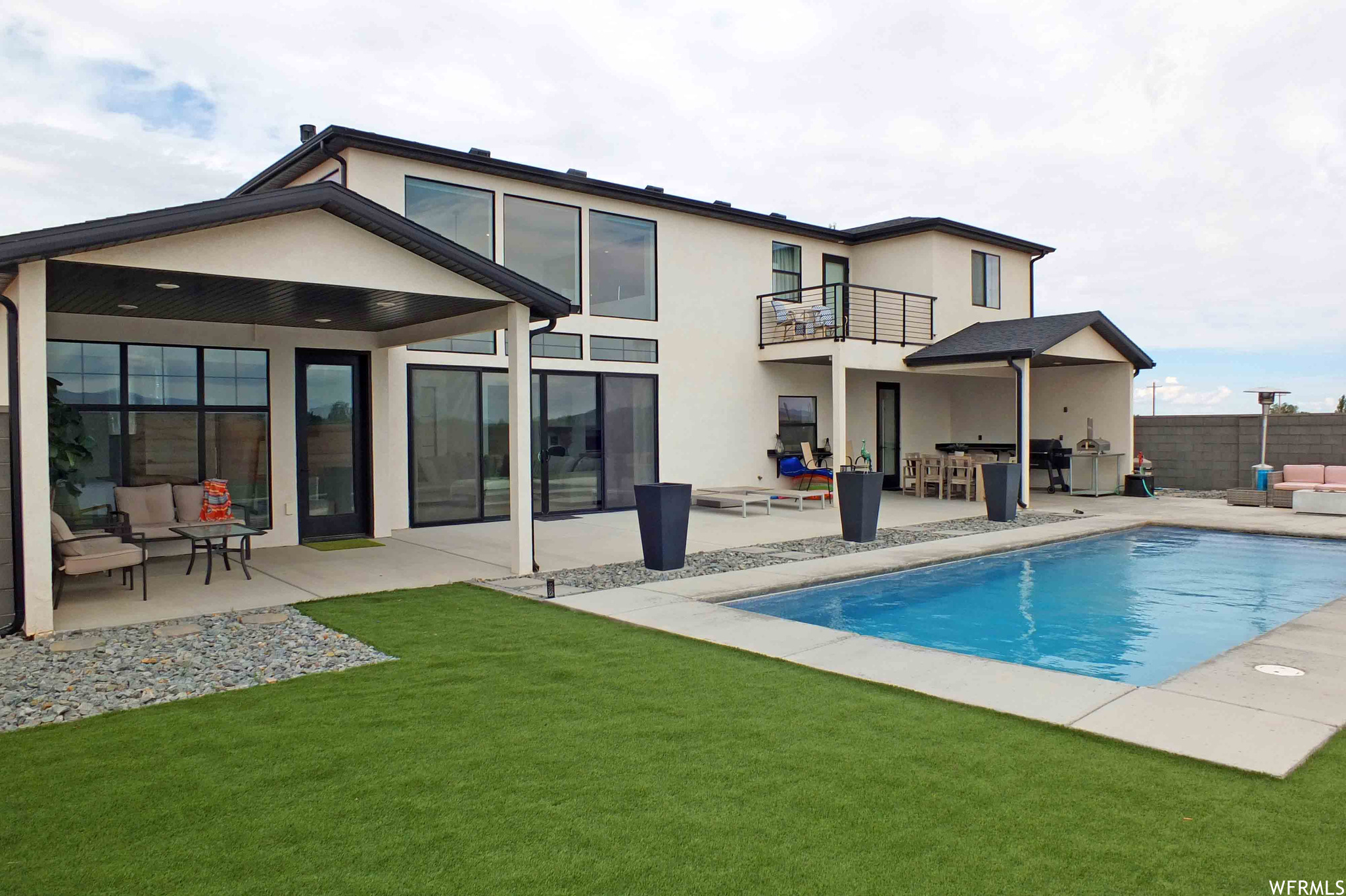 Rear view of house featuring a patio area, an outdoor living space, a fenced in pool, and a balcony