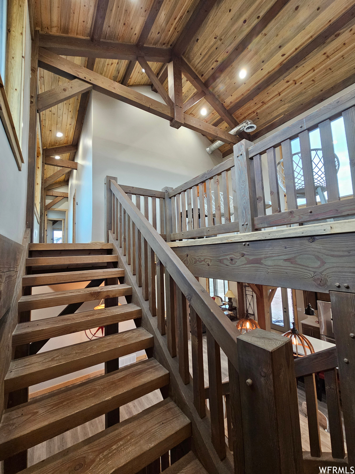Stairway featuring a wealth of natural light, wood ceiling and lofted ceiling with beams