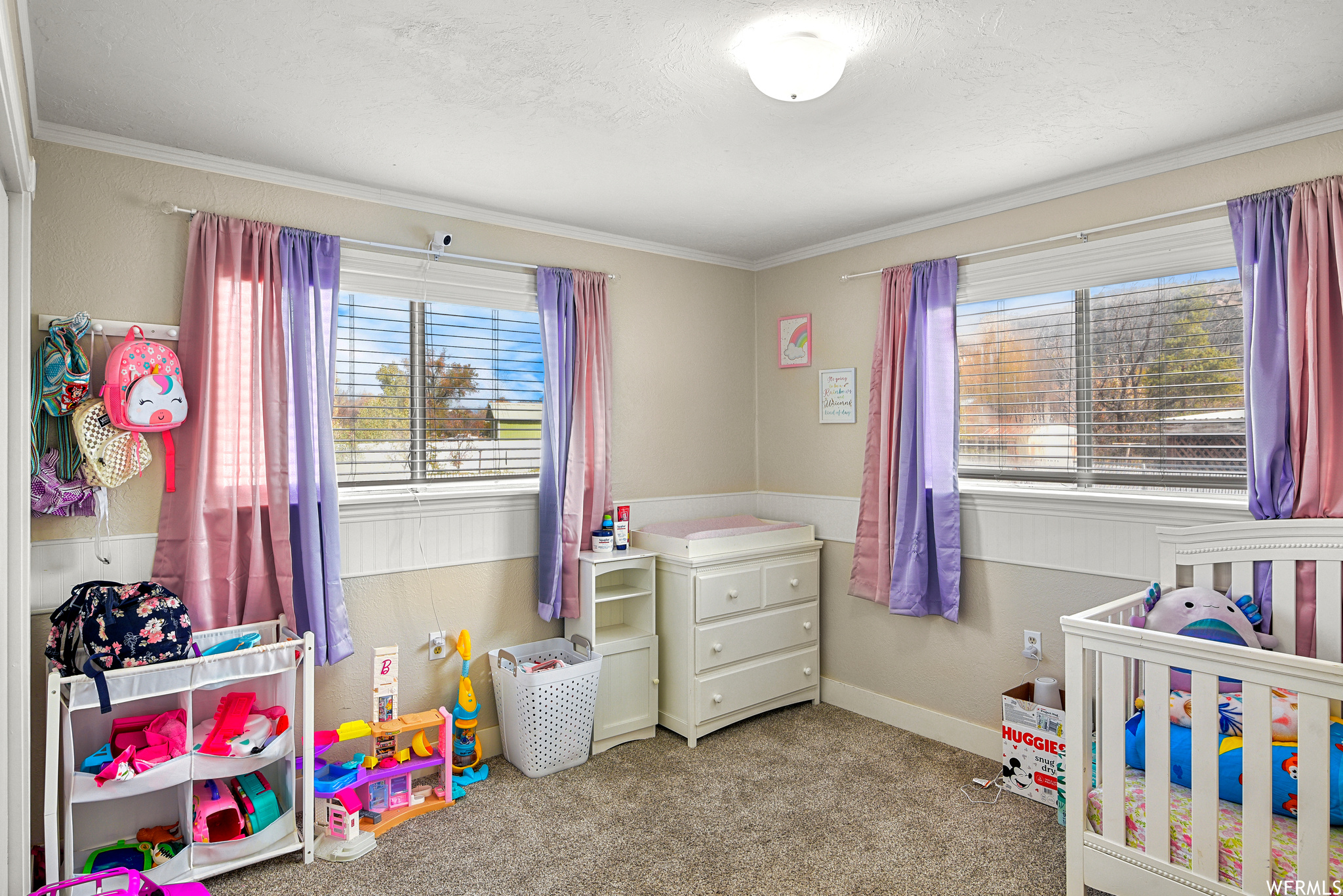 Carpeted bedroom featuring a nursery area and ornamental molding