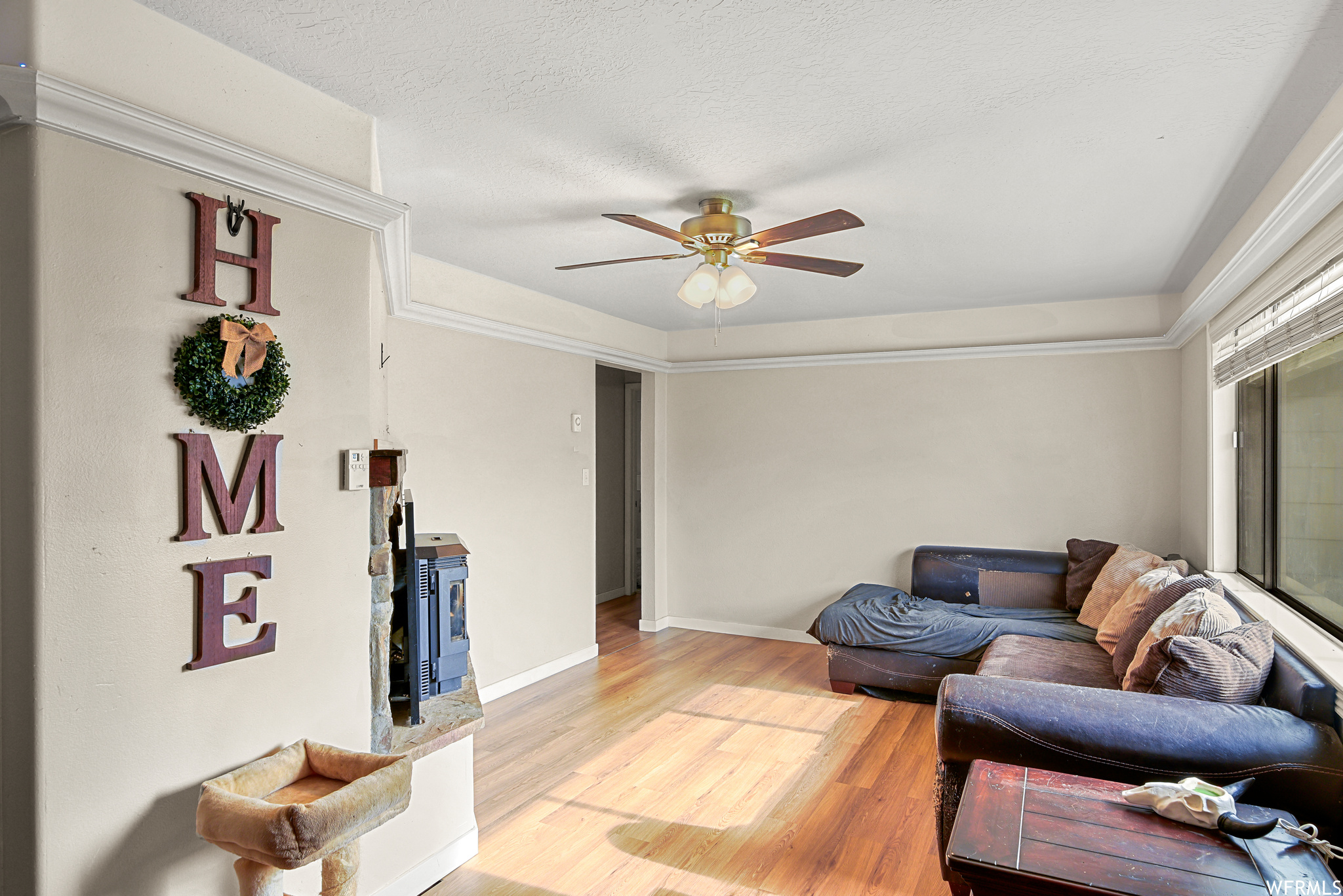 Living room with ceiling fan, light hardwood / wood-style flooring, and a textured ceiling