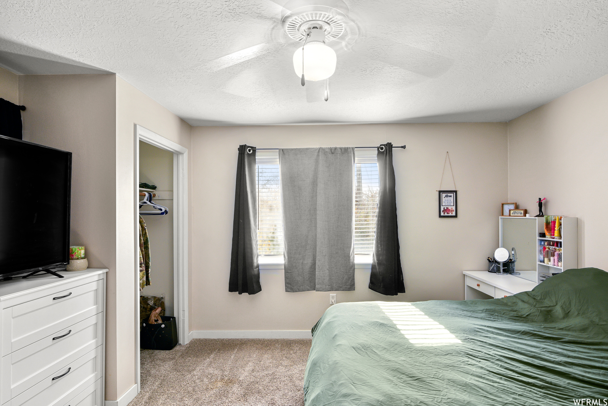 Carpeted bedroom with a closet, ceiling fan, and a textured ceiling