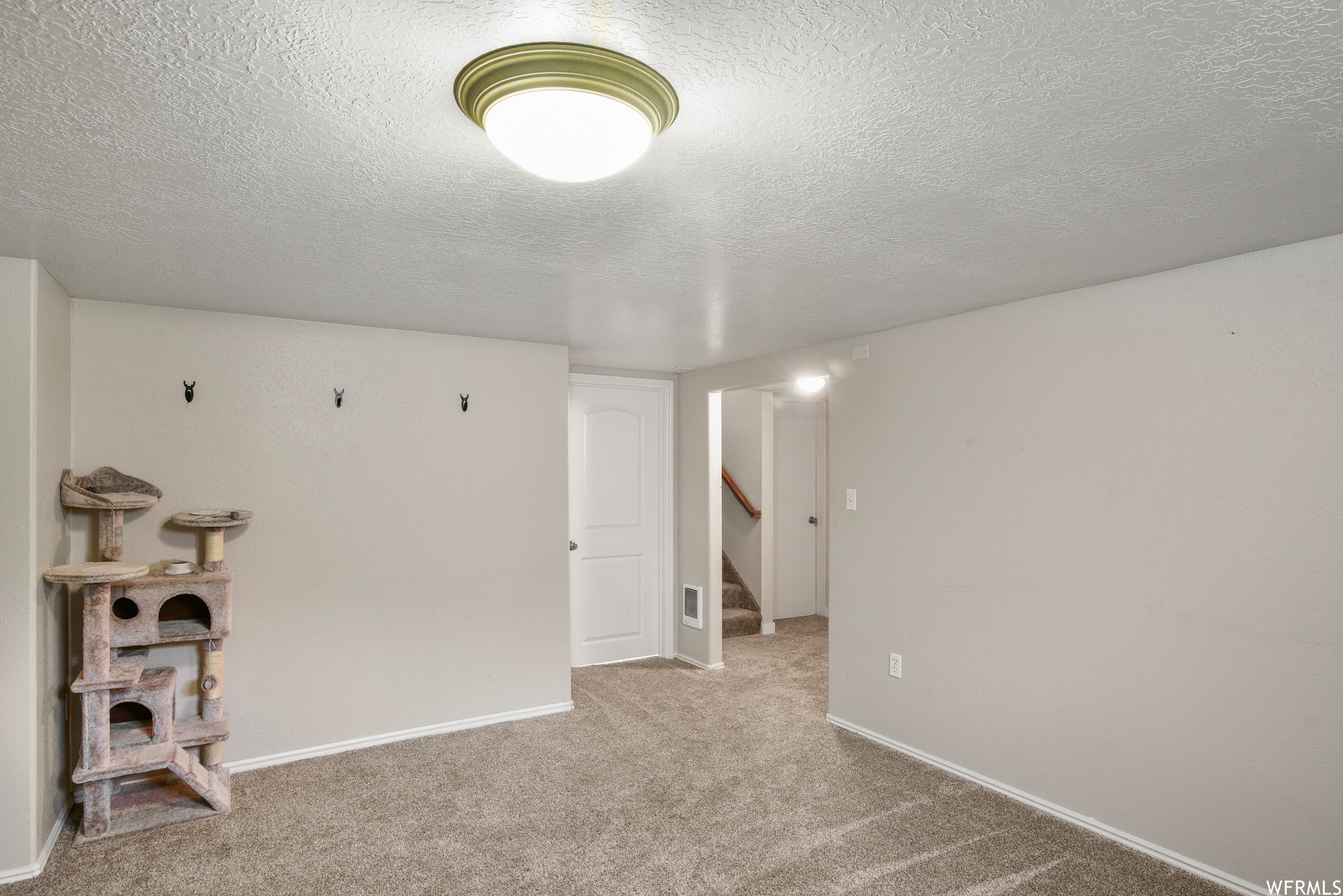 Basement with a textured ceiling and light carpet