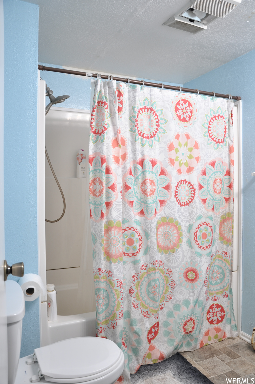 Bathroom featuring shower / bath combo with shower curtain, a textured ceiling, toilet, and tile floors