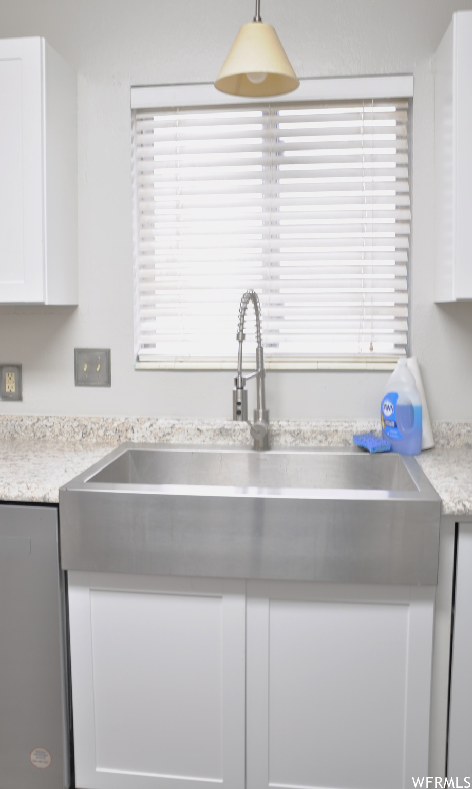 Kitchen featuring sink, decorative light fixtures, light stone counters, and white cabinets