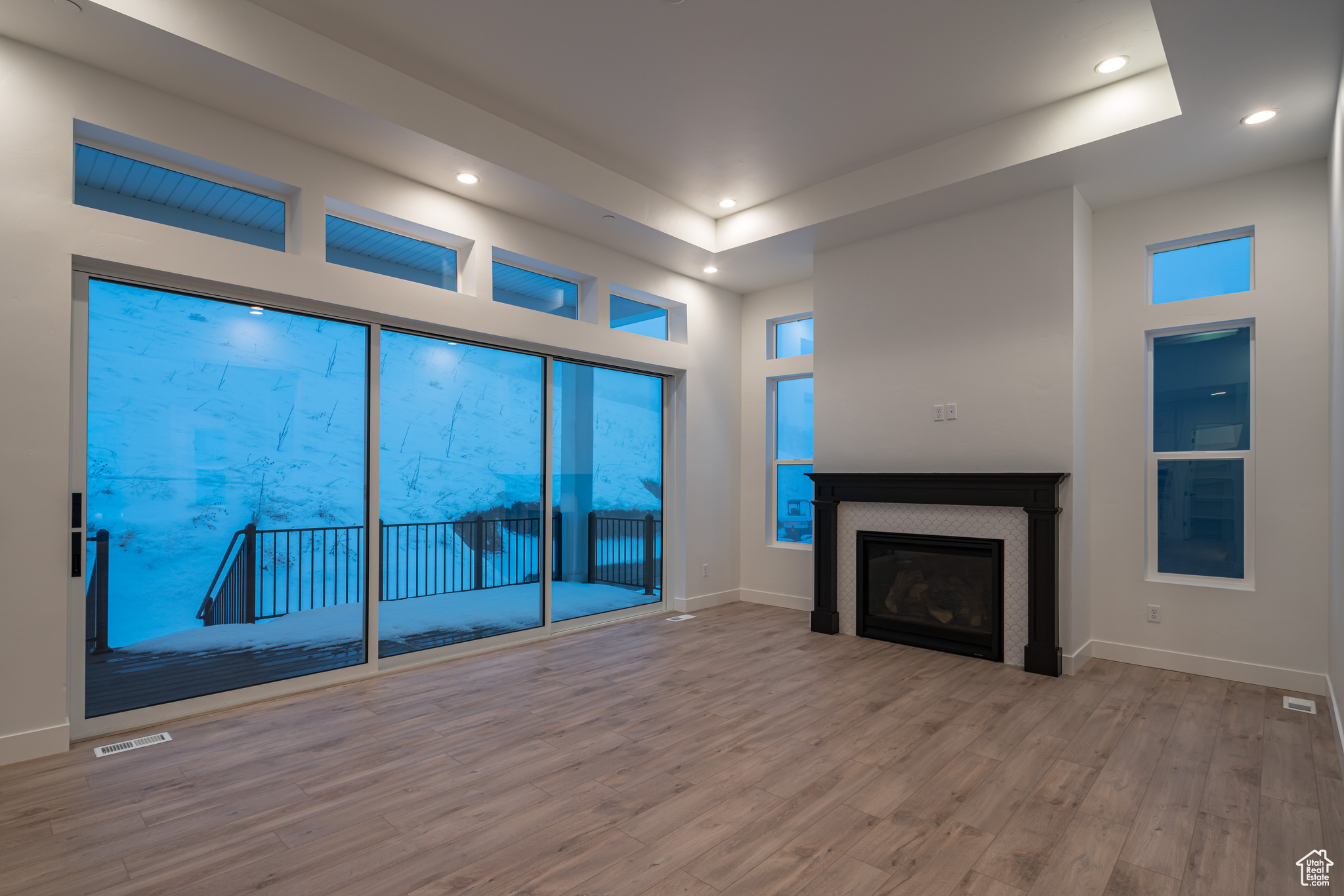 Unfurnished living room featuring light hardwood / wood-style flooring and a tray ceiling