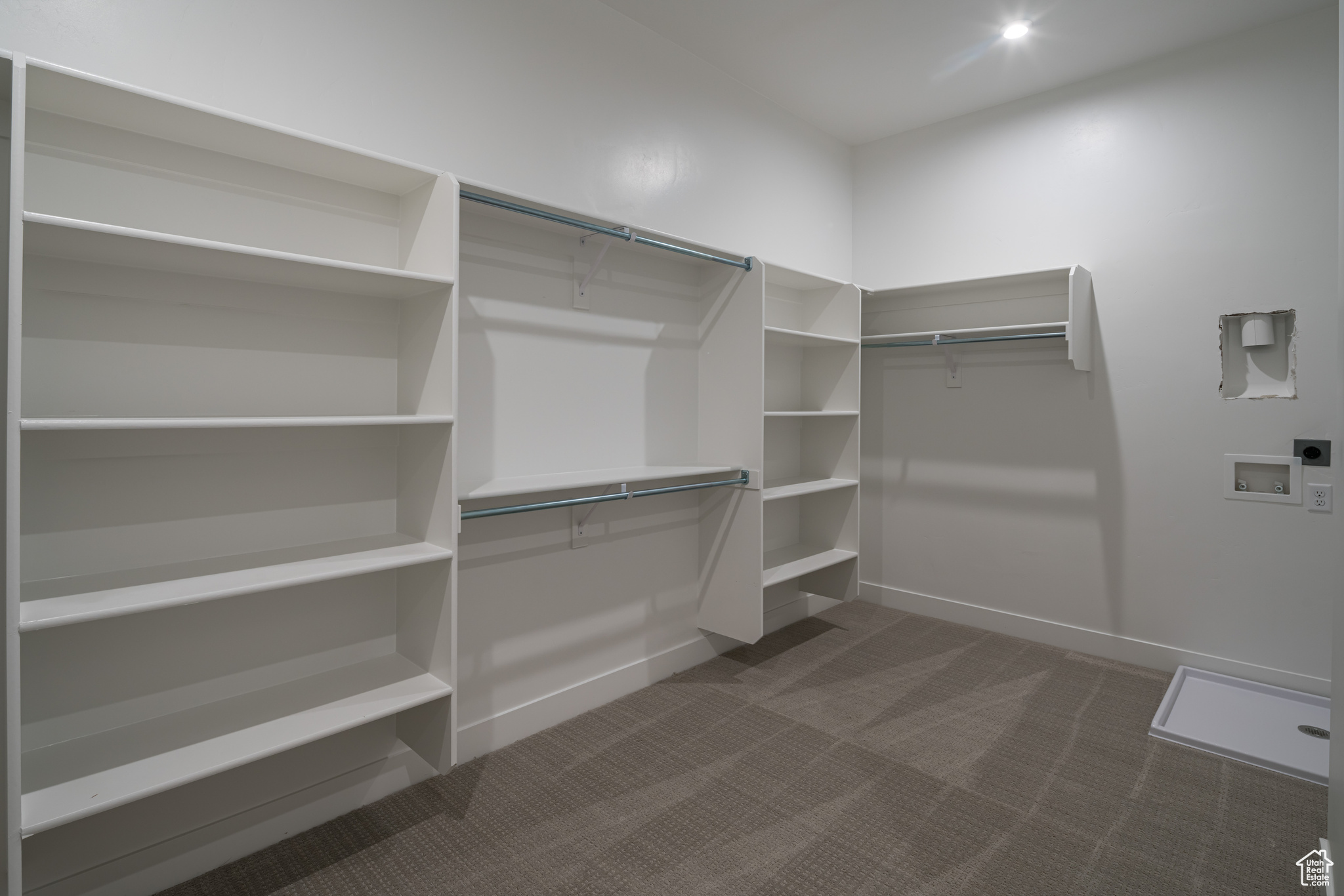 Spacious closet with dark colored carpet