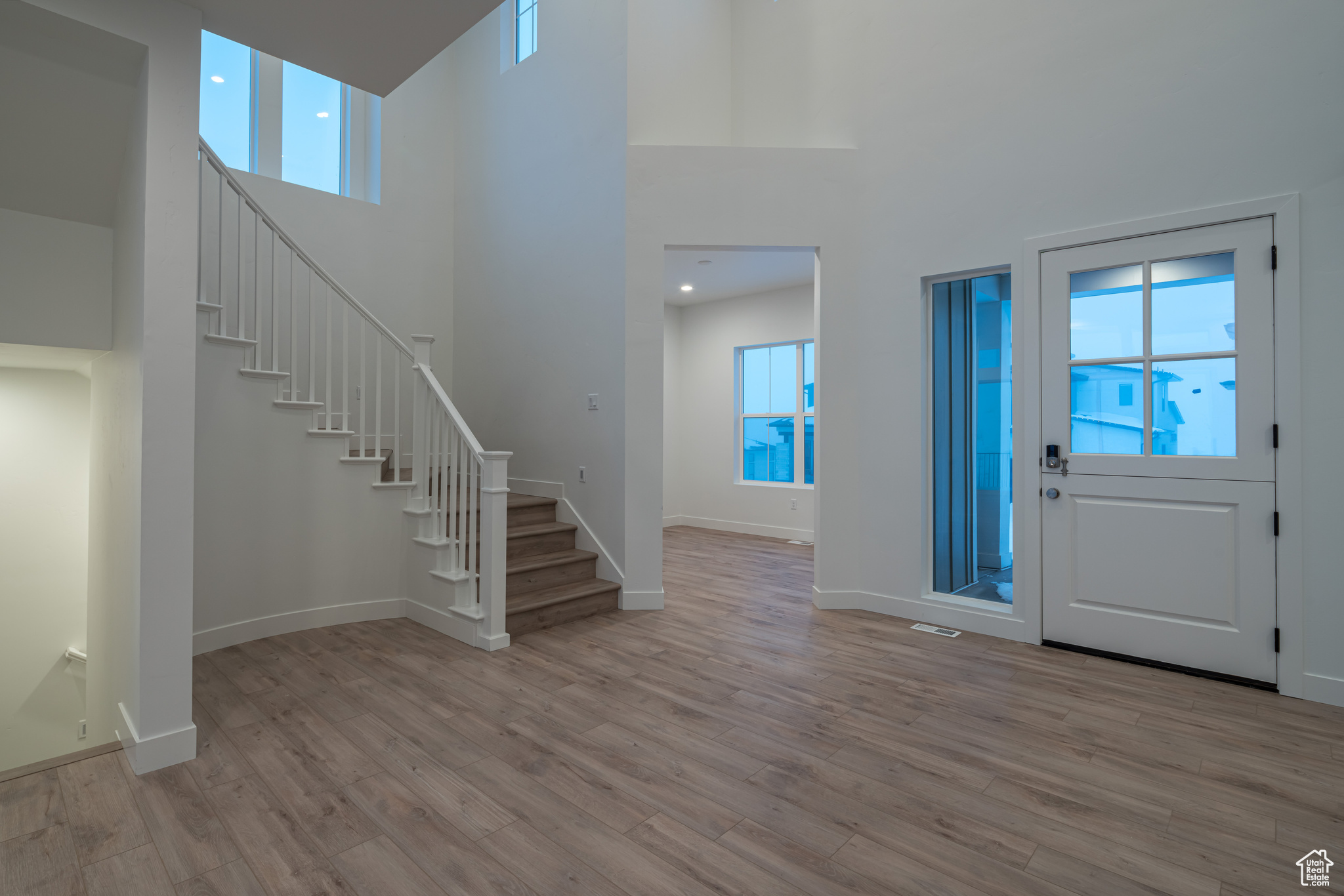 Entrance foyer with light hardwood / wood-style flooring and a towering ceiling