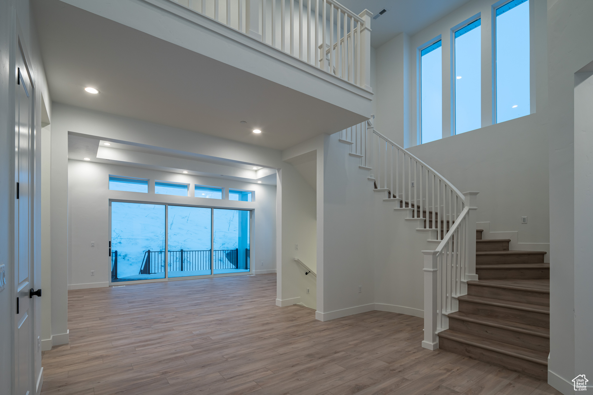 Stairs with plenty of natural light, light hardwood / wood-style flooring, and a high ceiling