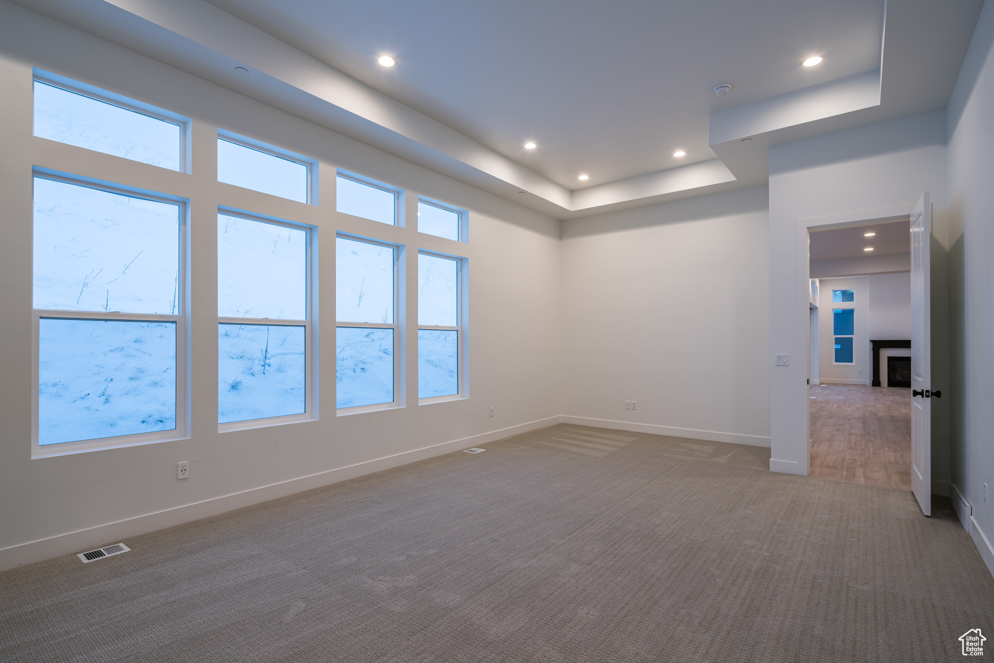 Unfurnished room with dark carpet, plenty of natural light, and a raised ceiling