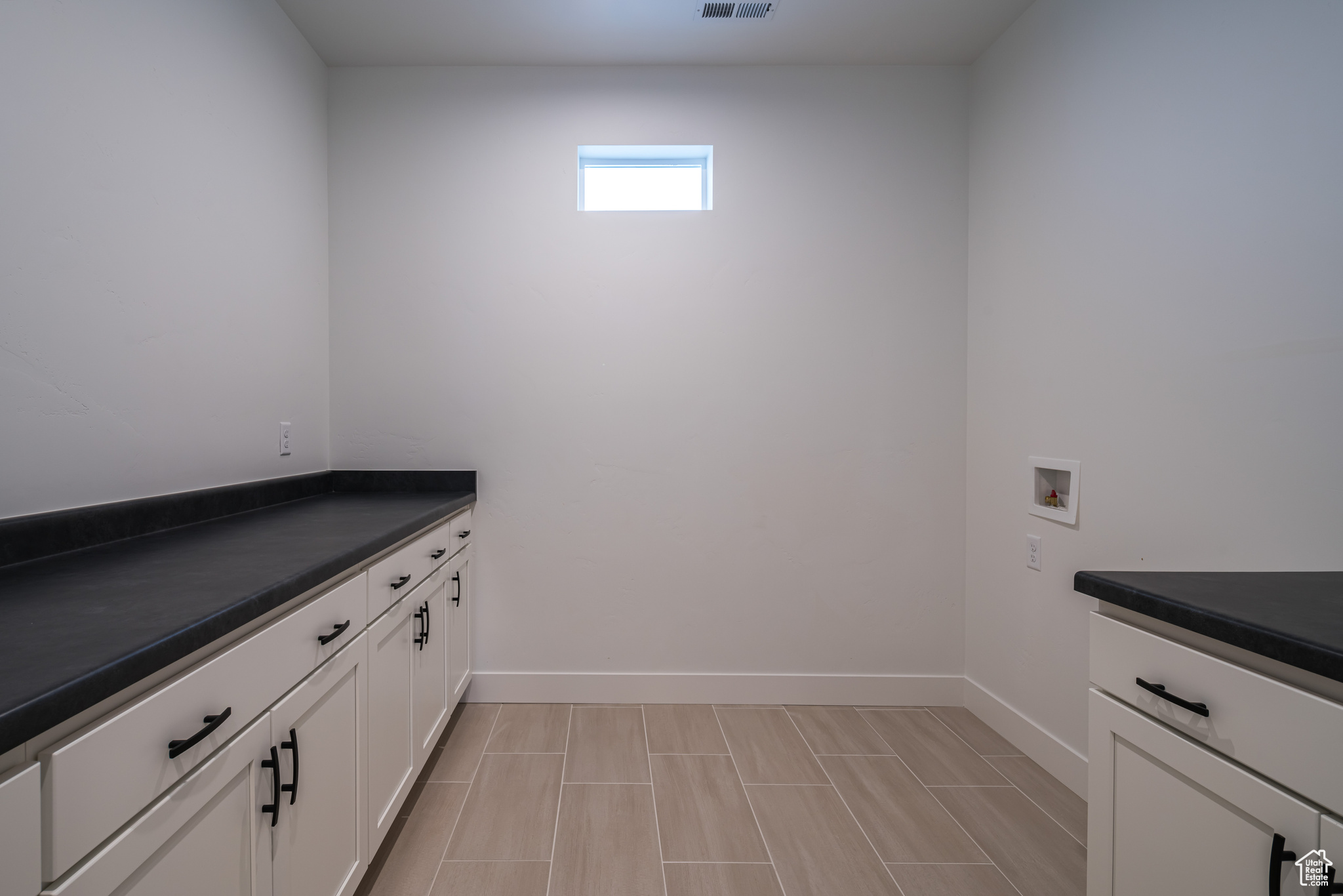 Laundry area with cabinets, light tile floors, and washer hookup