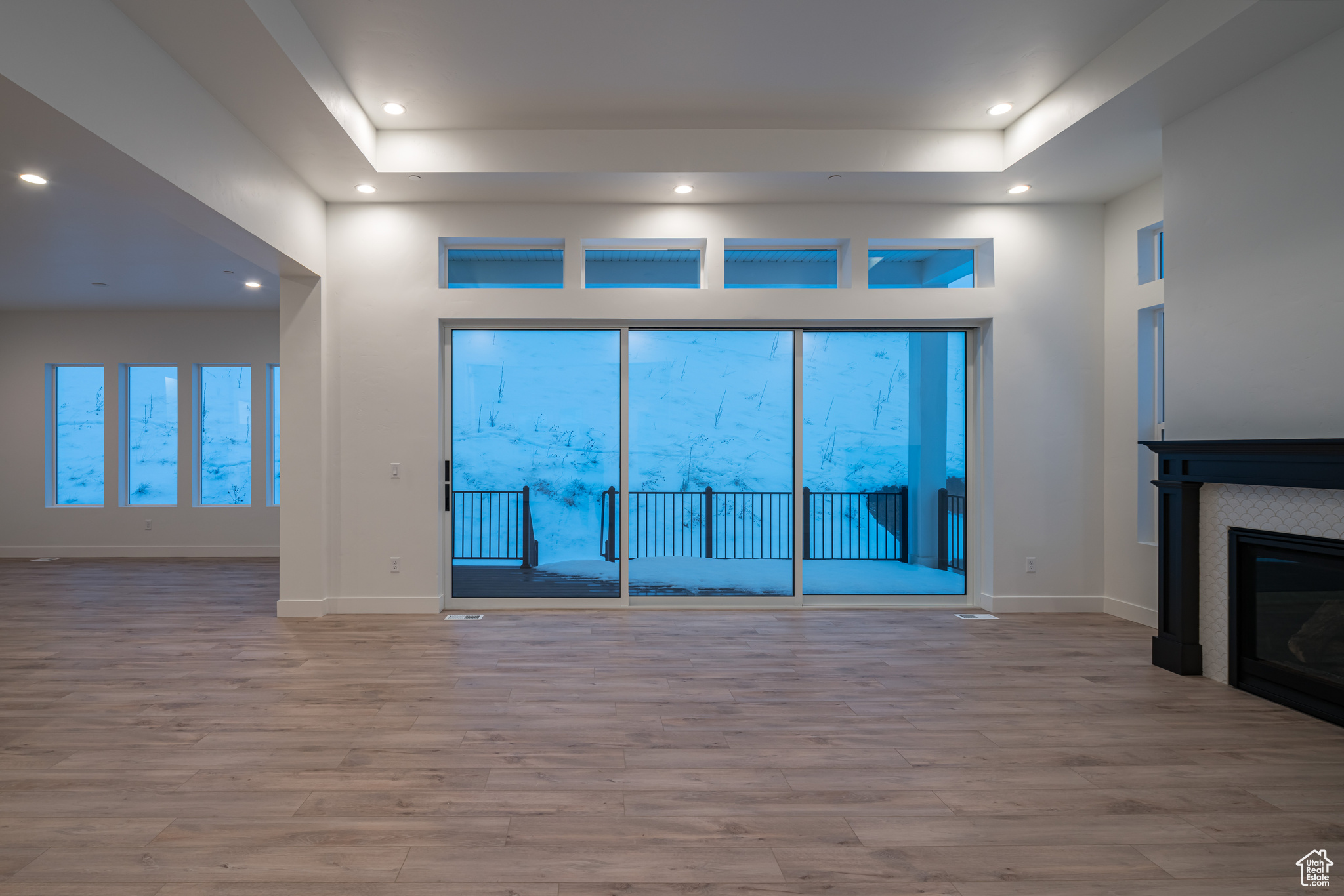 Unfurnished living room with a tray ceiling and light wood-type flooring