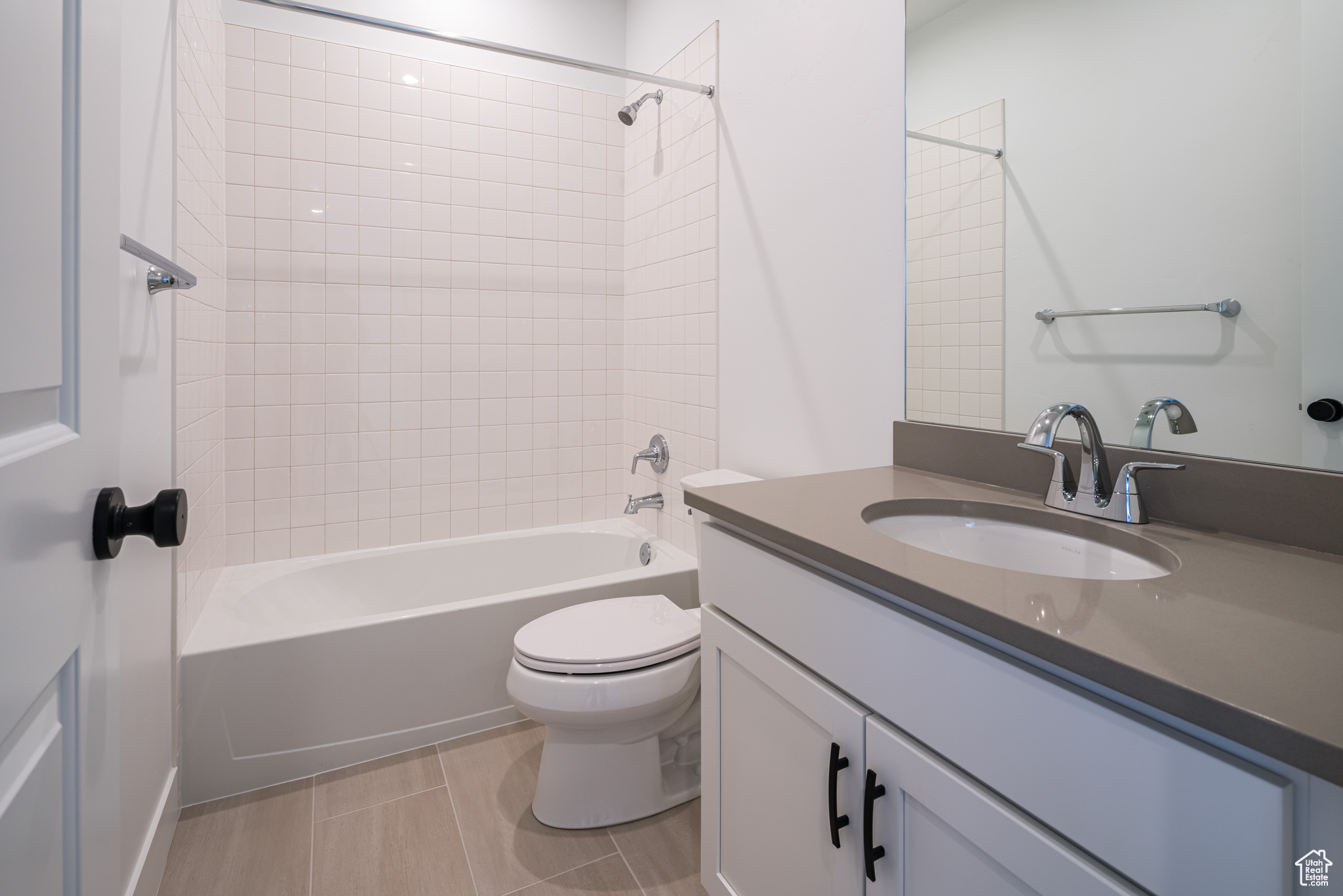 Full bathroom featuring toilet, tiled shower / bath, oversized vanity, and tile flooring