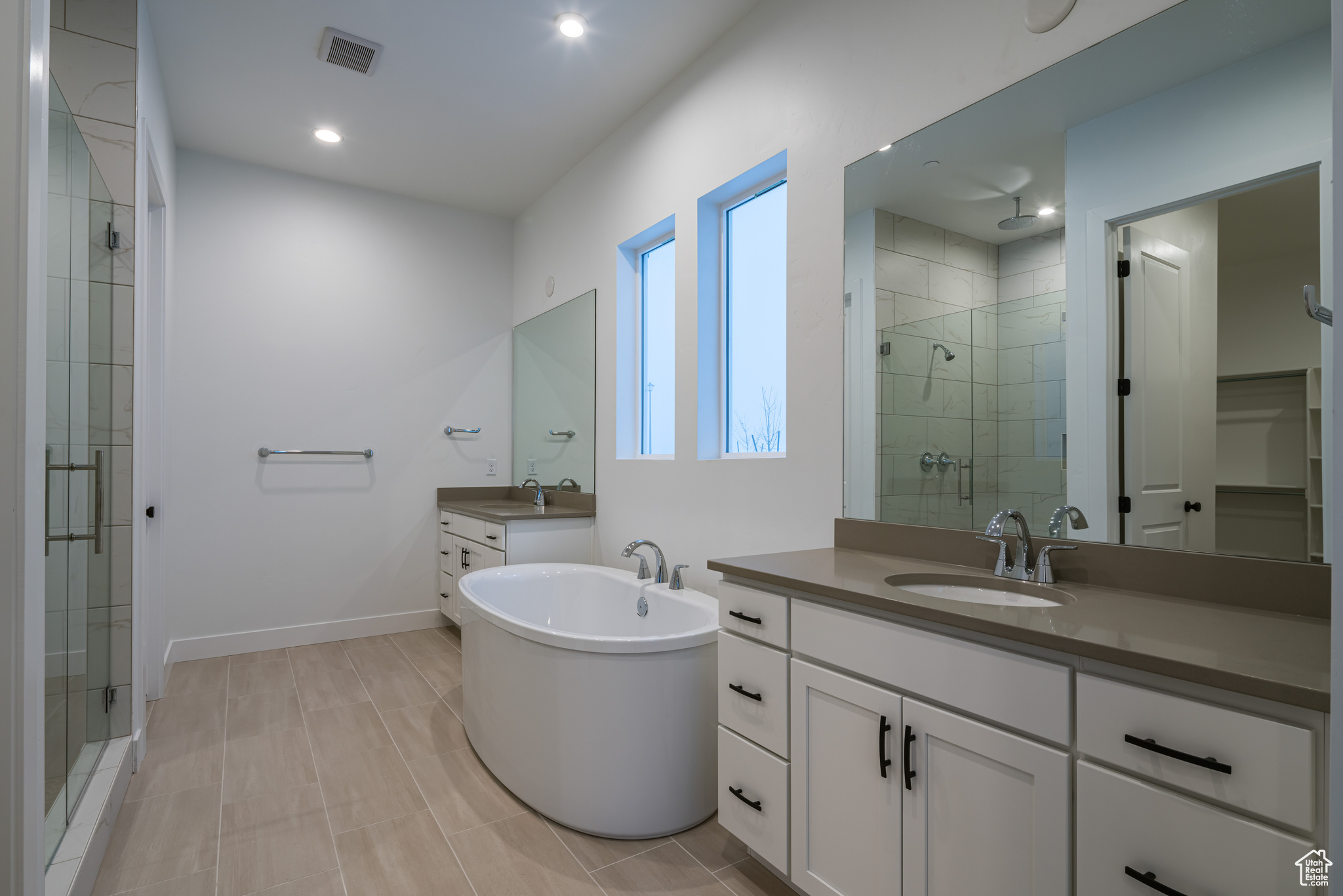 Bathroom with dual bowl vanity, tile flooring, and separate shower and tub