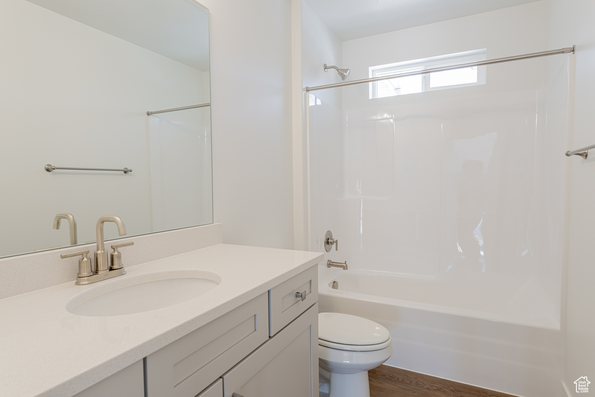 Full bathroom with hardwood / wood-style flooring, toilet, vanity, and washtub / shower combination