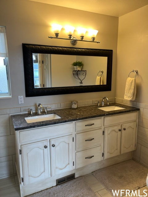 Bathroom featuring double sink, tile flooring, tile walls, and large vanity