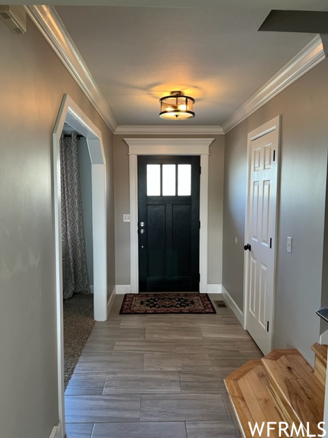 Foyer entrance with light colored carpet and crown molding
