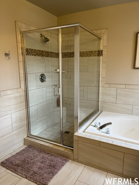 Bathroom featuring tile flooring and shower with separate bathtub