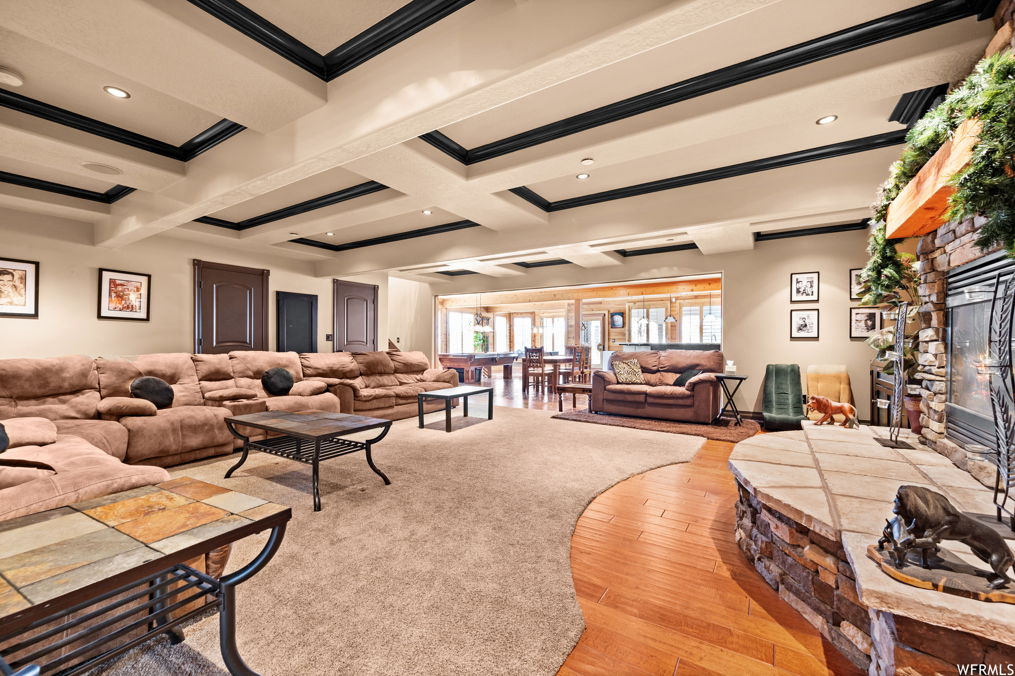 Living room featuring coffered ceiling, light wood-type flooring, a fireplace, ornamental molding, and beamed ceiling