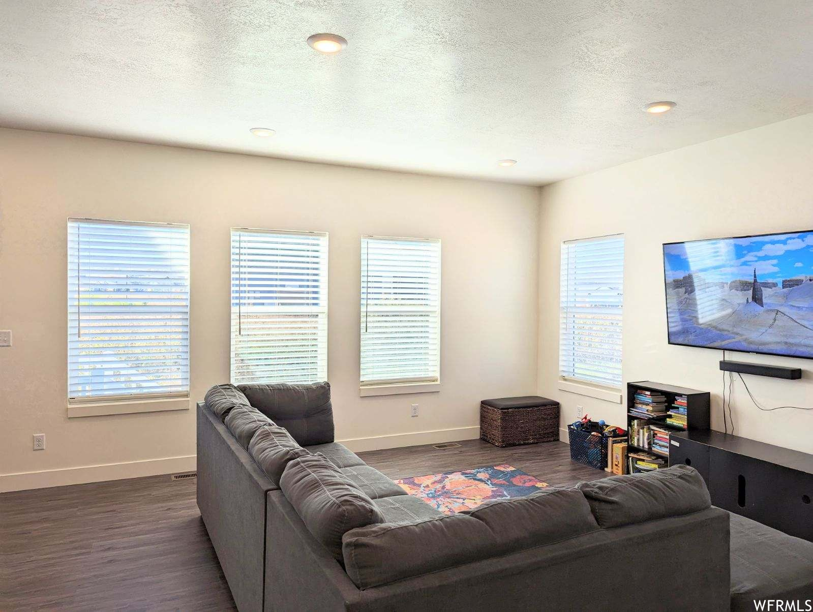 Living room with dark hardwood / wood-style floors and a textured ceiling
