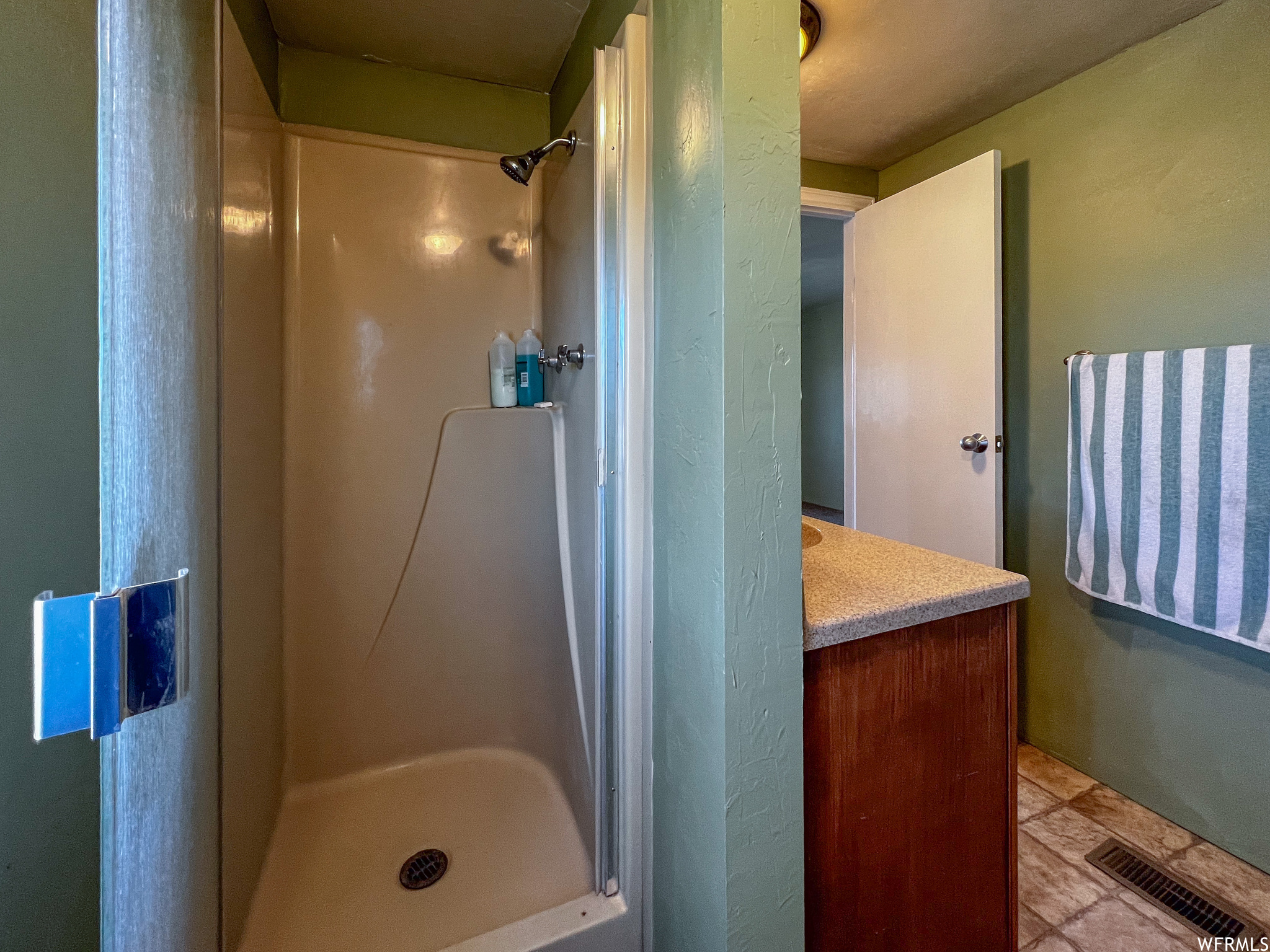 Bathroom featuring tile floors, walk in shower, and vanity